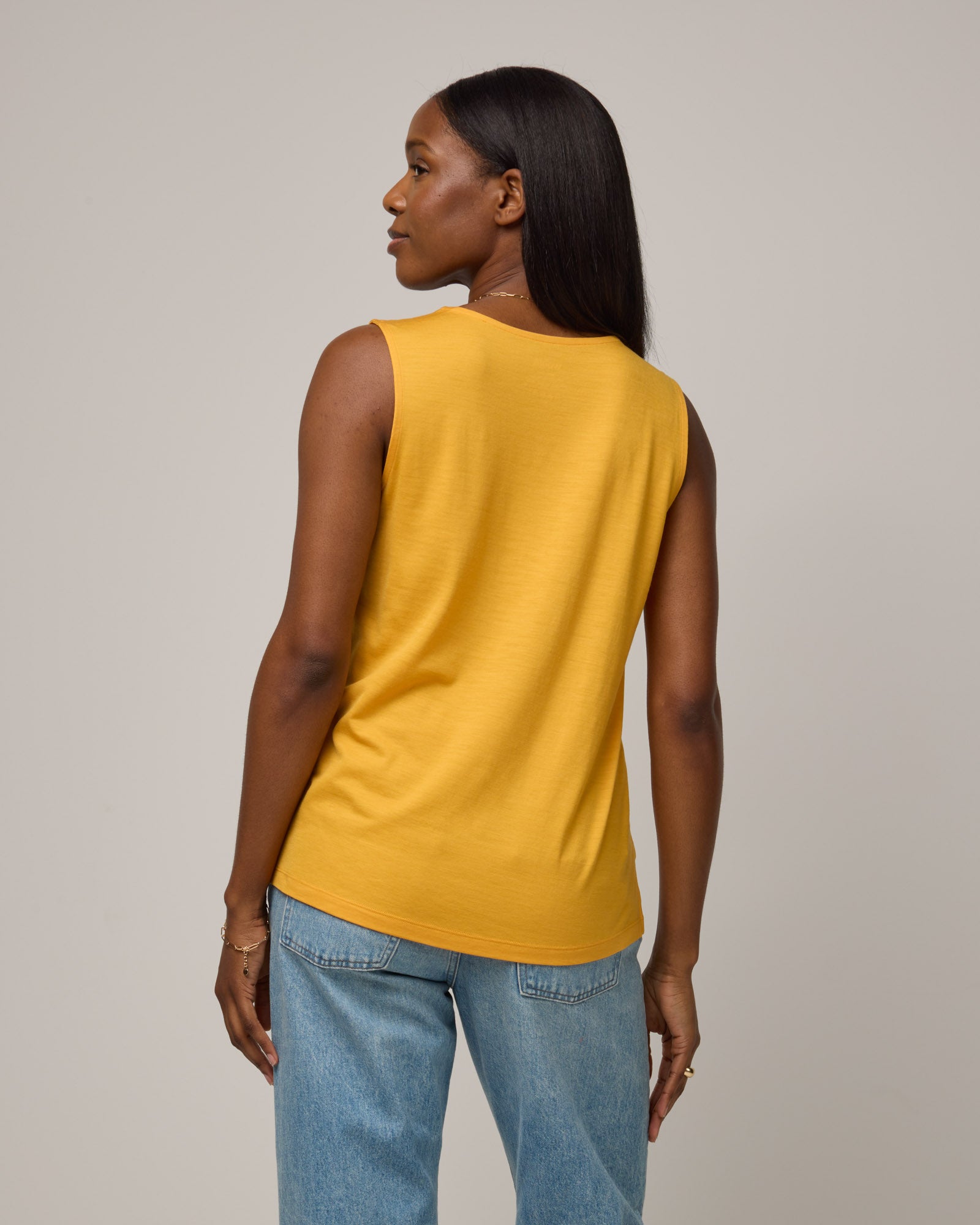 Model wearing Steph Scoop Neck Tank in Mango, a bright yellow-orange color. Steph Scoop Neck Tank is a merino wool sleeveless tank available in sizes XS-3X. 