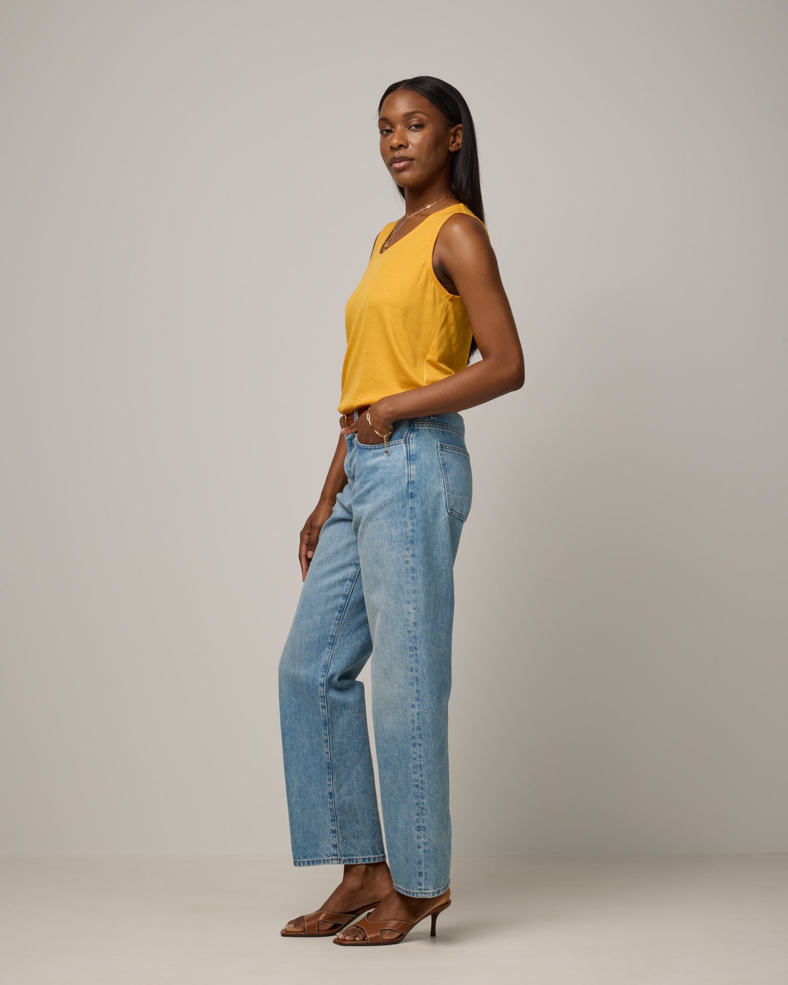 Model wearing Steph Scoop Neck Tank in Mango, a bright yellow-orange color. Steph Scoop Neck Tank is a merino wool sleeveless tank available in sizes XS-3X. 