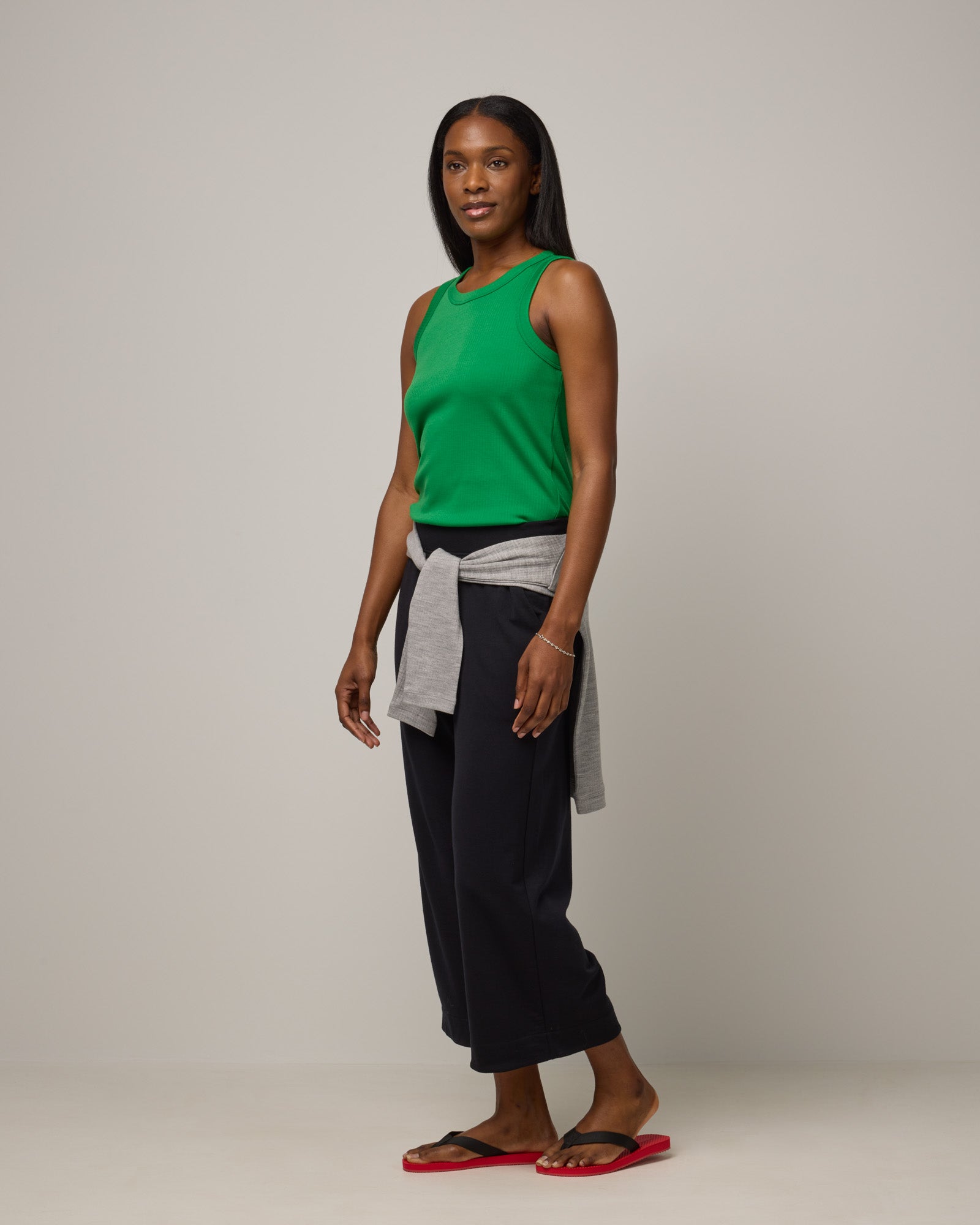Model wearing Lily Ribbed Tee in Verde, a bright Kelly green color. Lily Ribbed Tee is a merino wool sleeveless, crew neck tank available in sizes XS-3X. 