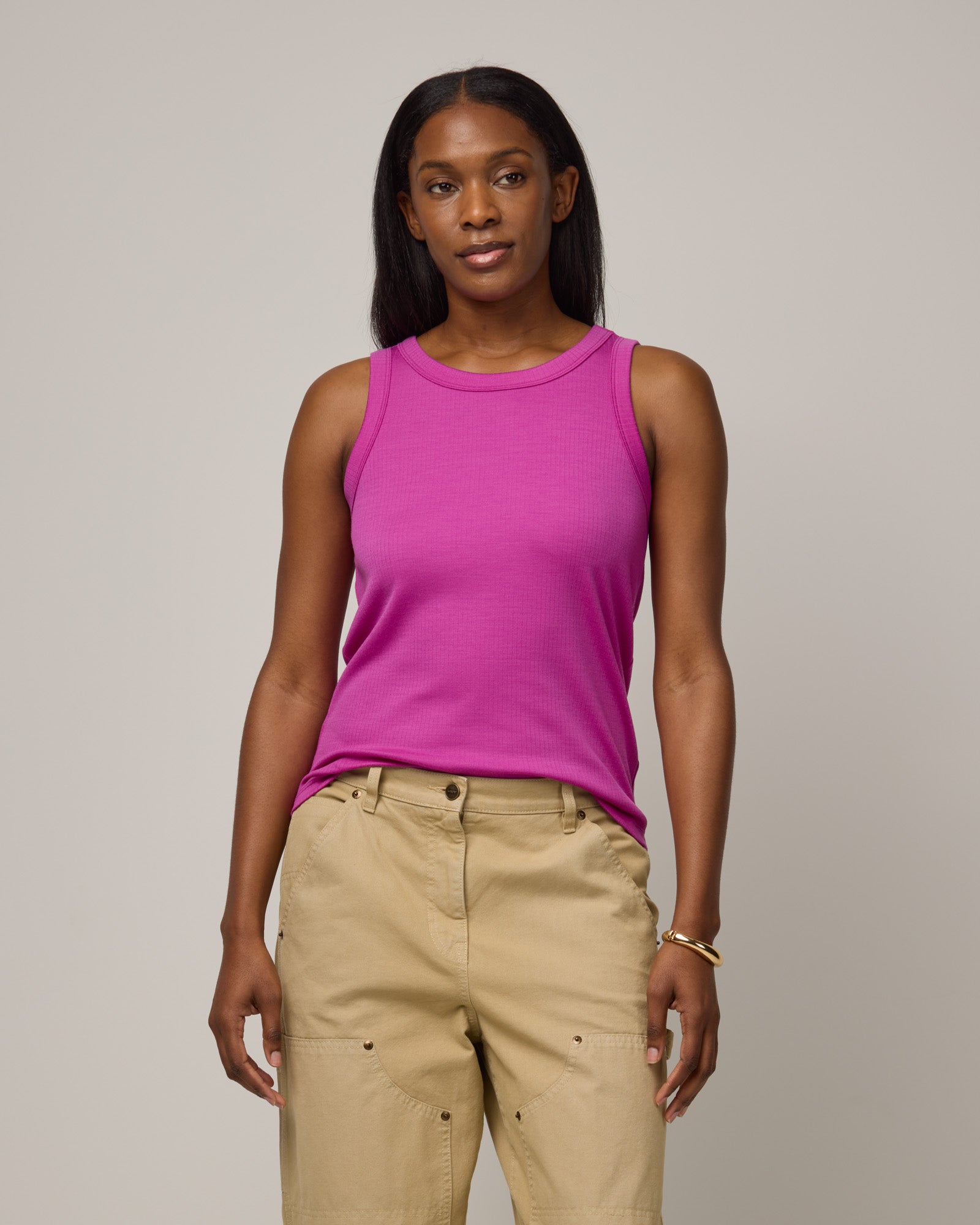Model wearing Lily Ribbed Tee in Petunia, a bright fuchsia pink-purple color. Lily Ribbed Tee is a merino wool sleeveless, crew neck tank available in sizes XS-3X. 