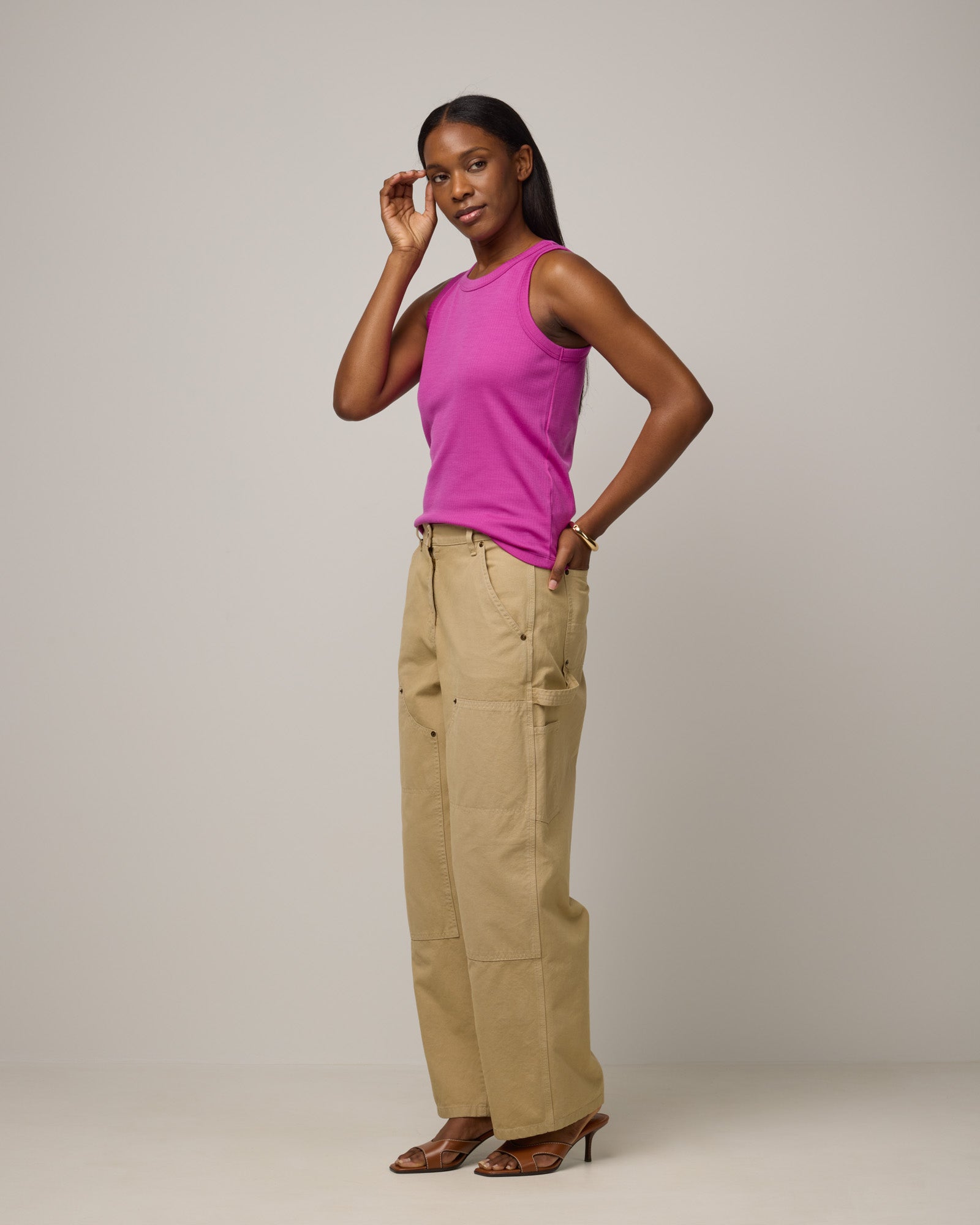 Model wearing Lily Ribbed Tee in Petunia, a bright fuchsia pink-purple color. Lily Ribbed Tee is a merino wool sleeveless, crew neck tank available in sizes XS-3X. 