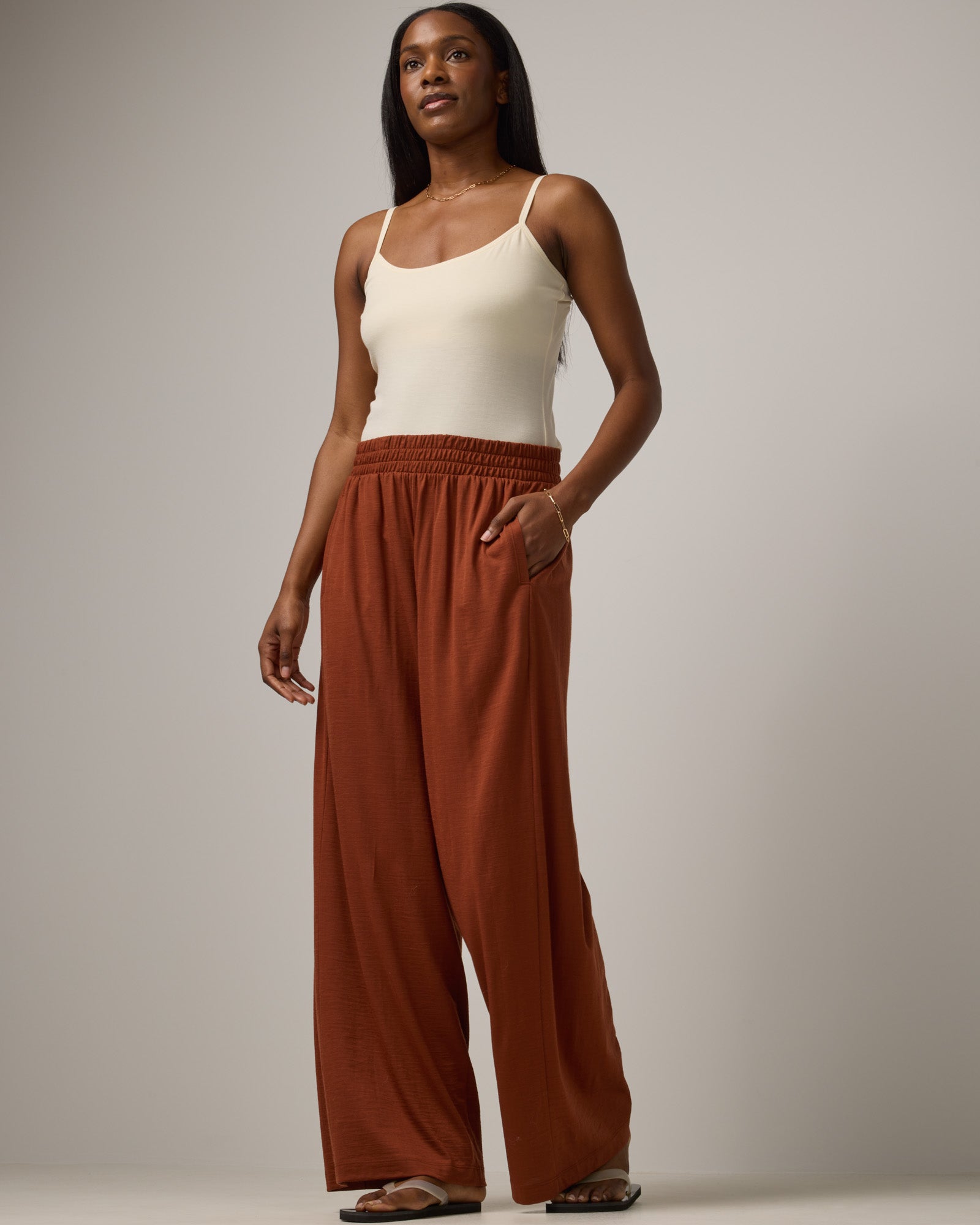 Model wearing Lisbon Palazzo Pant in Cinnamon, a reddish-brown rust color. Lisbon Palazzo Pant is a merino wool easy pant available in sizes XS-3X. 