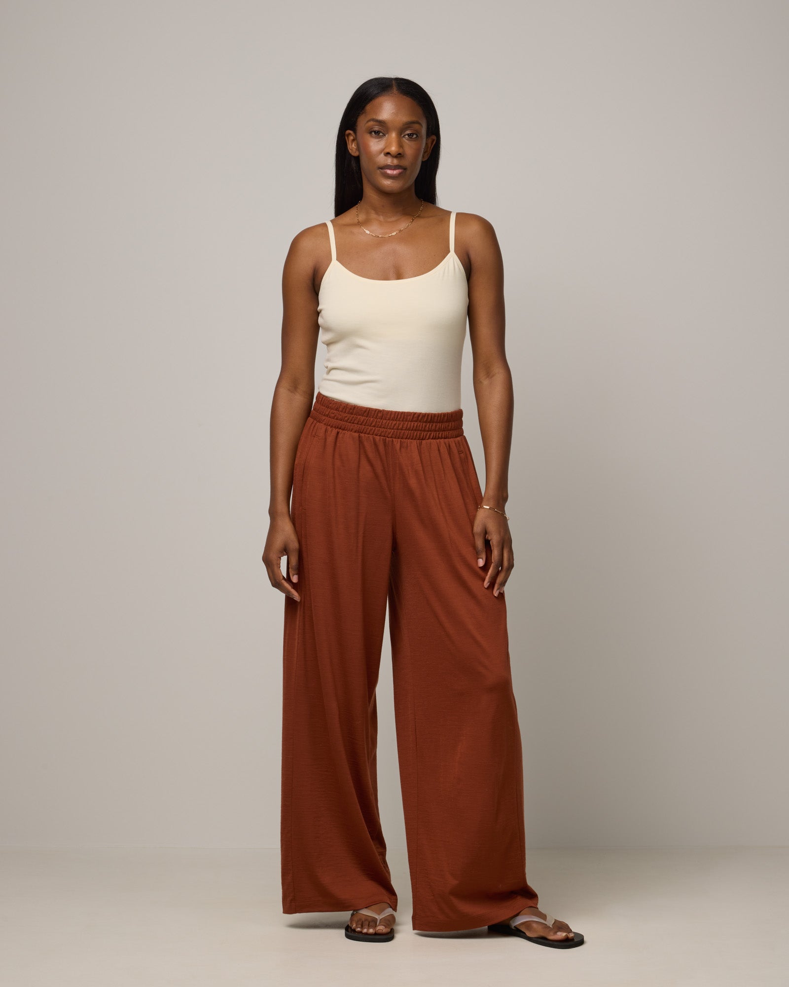 Model wearing Lisbon Palazzo Pant in Cinnamon, a reddish-brown rust color. Lisbon Palazzo Pant is a merino wool easy pant available in sizes XS-3X. 