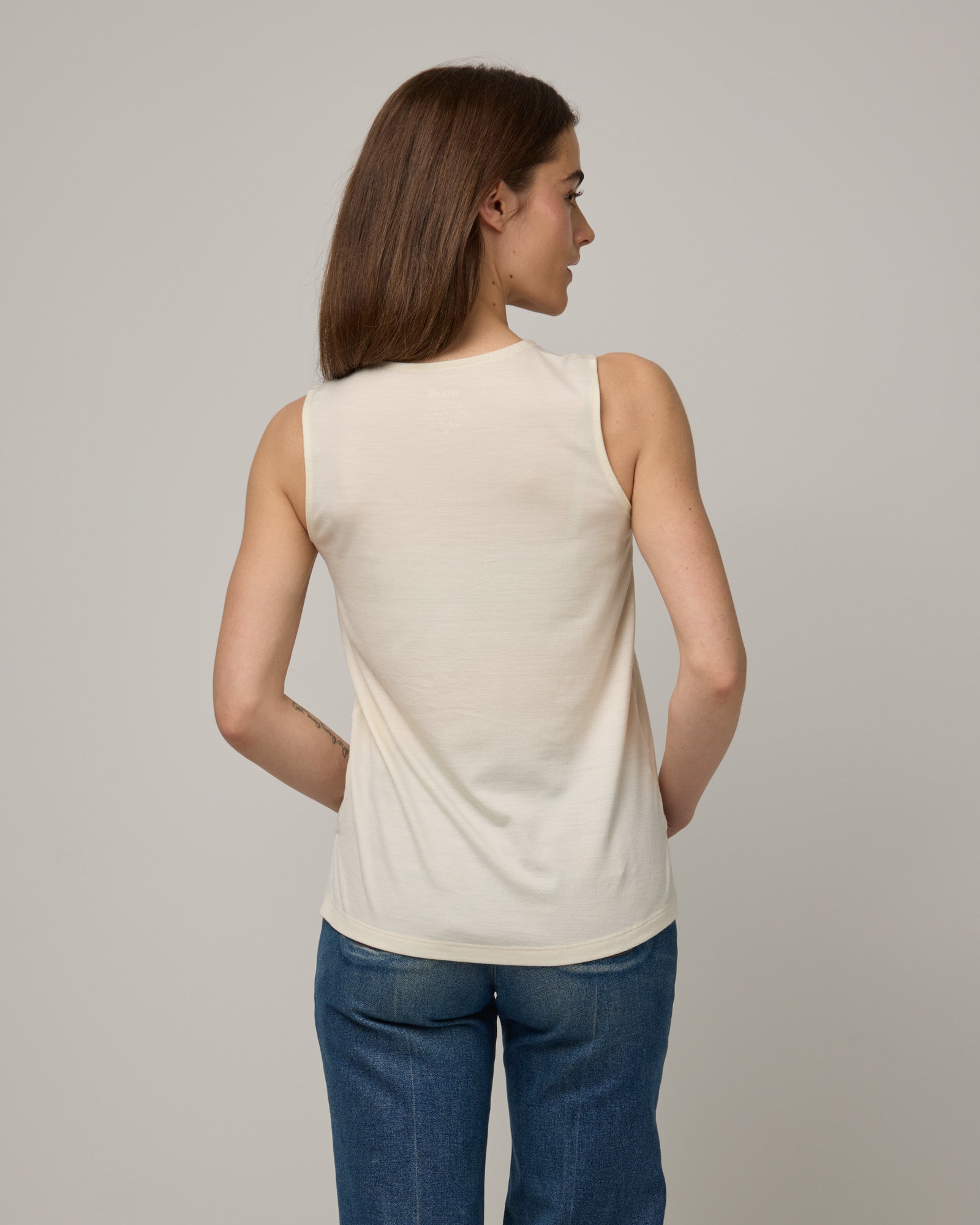 Model wearing Steph Scoop Neck Tank in Natural White. Steph Scoop Neck Tank is a merino wool sleeveless tank available in sizes XS-3X.  