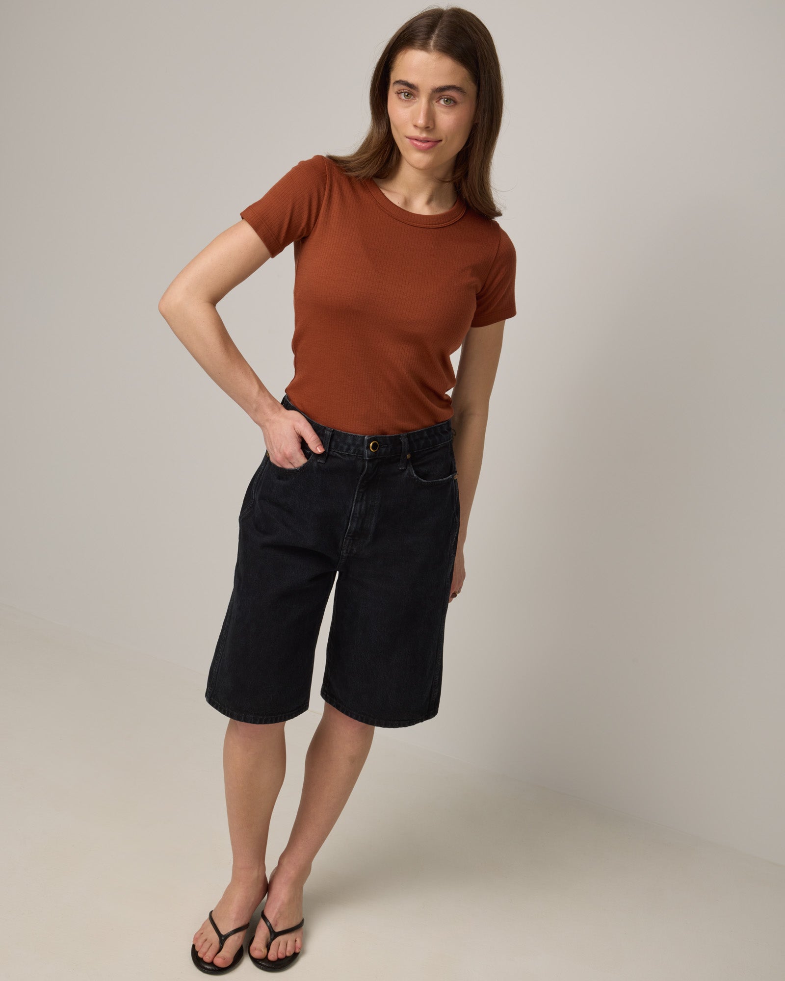Model wearing Taylor Ribbed Tee in Cinnamon, a reddish-brown rust color. Taylor Ribbed Tee is a merino wool short sleeve, crew neck tee available in sizes XS-3X.