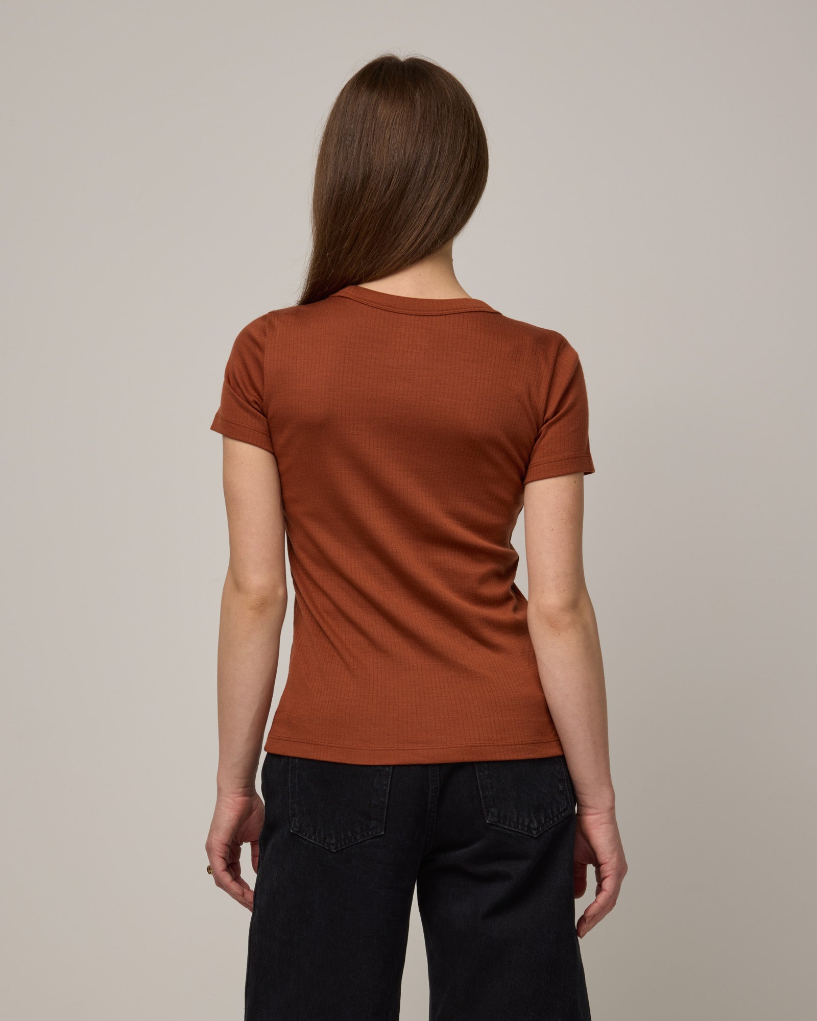 Model wearing Taylor Ribbed Tee in Cinnamon, a reddish-brown rust color. Taylor Ribbed Tee is a merino wool short sleeve, crew neck tee available in sizes XS-3X.
