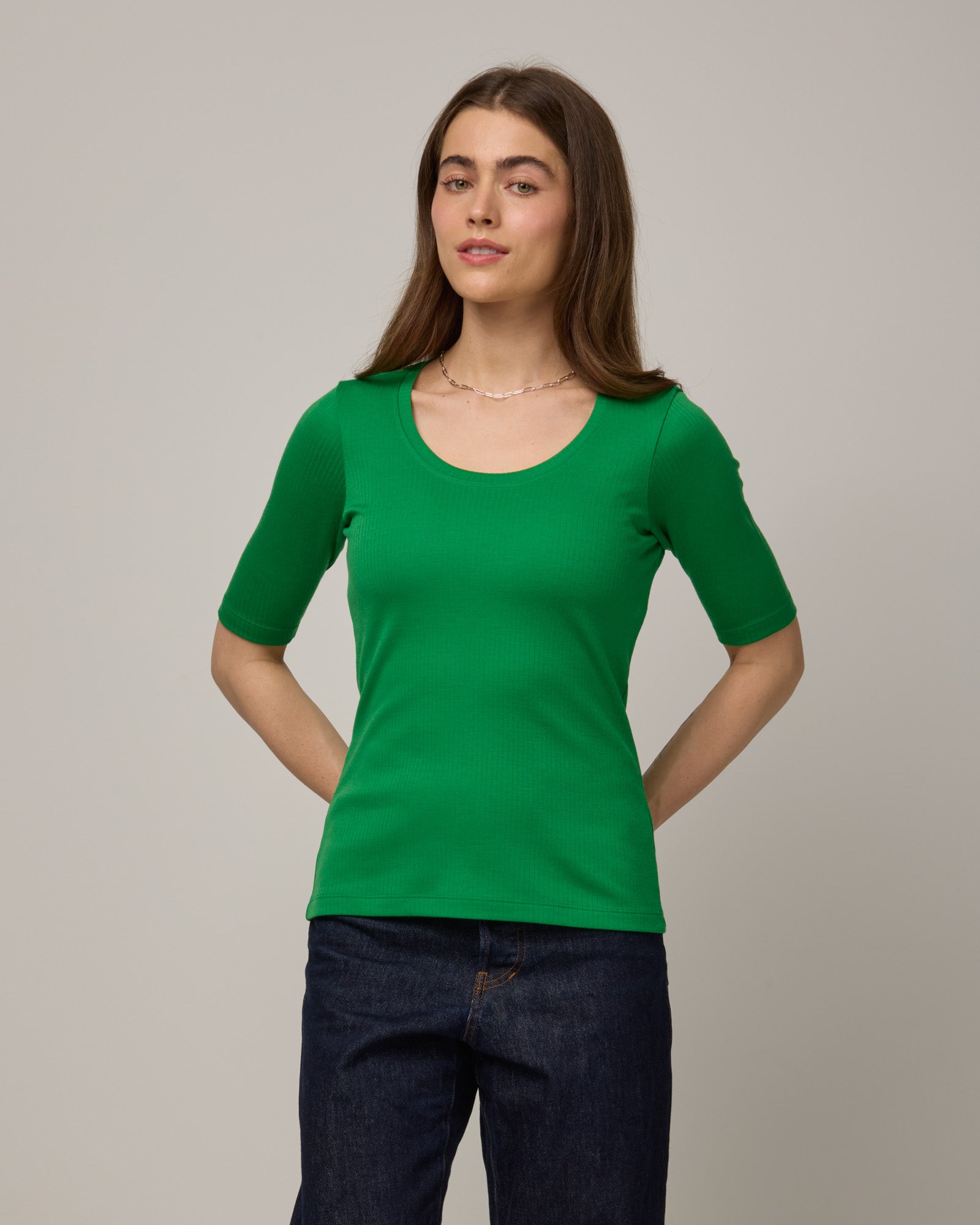Model wearing Celine Ribbed Elbow Sleeve Tee in Verde, a bright Kelly green color. Celine Ribbed Elbow Sleeve Tee is a merino wool short sleeve, scoop neck tee available in sizes XS-3X.