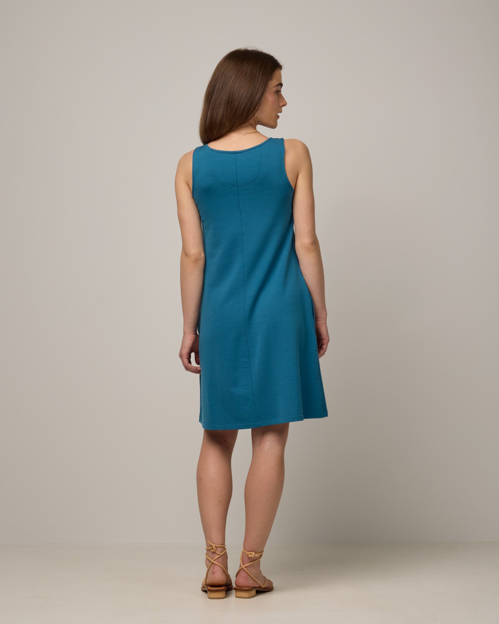 Model wearing Drew Tank Dress in Ocean Teal, a medium blue-green color. Drew Tank Dress is a merino wool sleeveless, scoop neck, knee-length swing dress available in sizes XS-3X. 