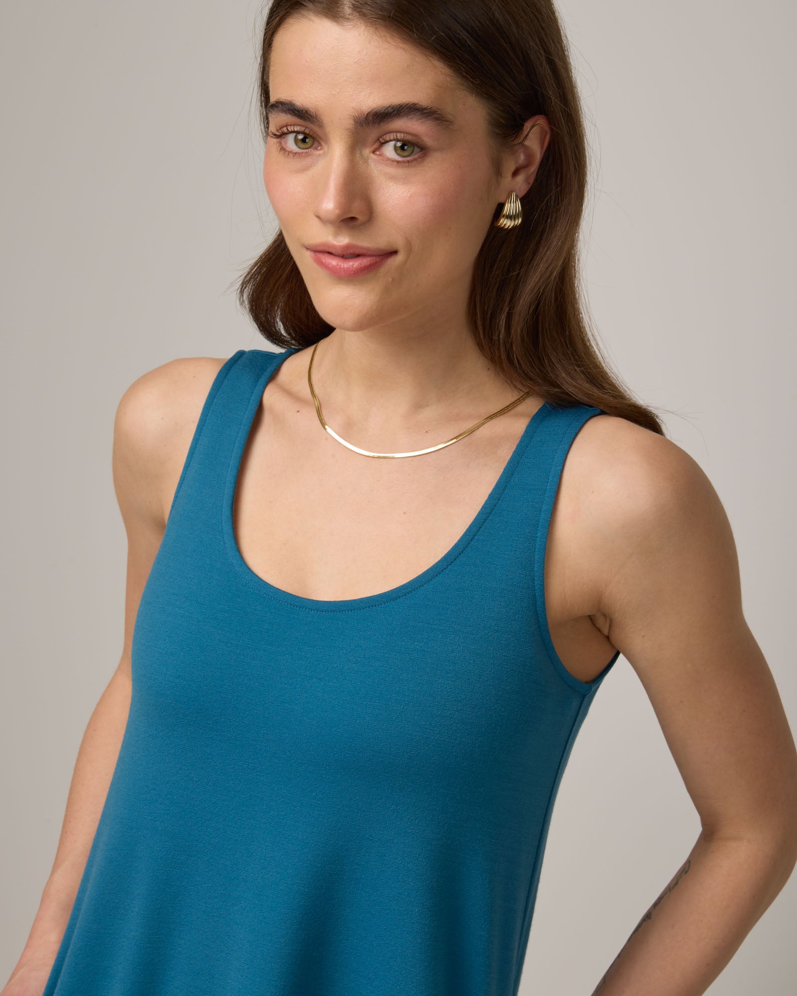 Model wearing Drew Tank Dress in Ocean Teal, a medium blue-green color. Drew Tank Dress is a merino wool sleeveless, scoop neck, knee-length swing dress available in sizes XS-3X. 