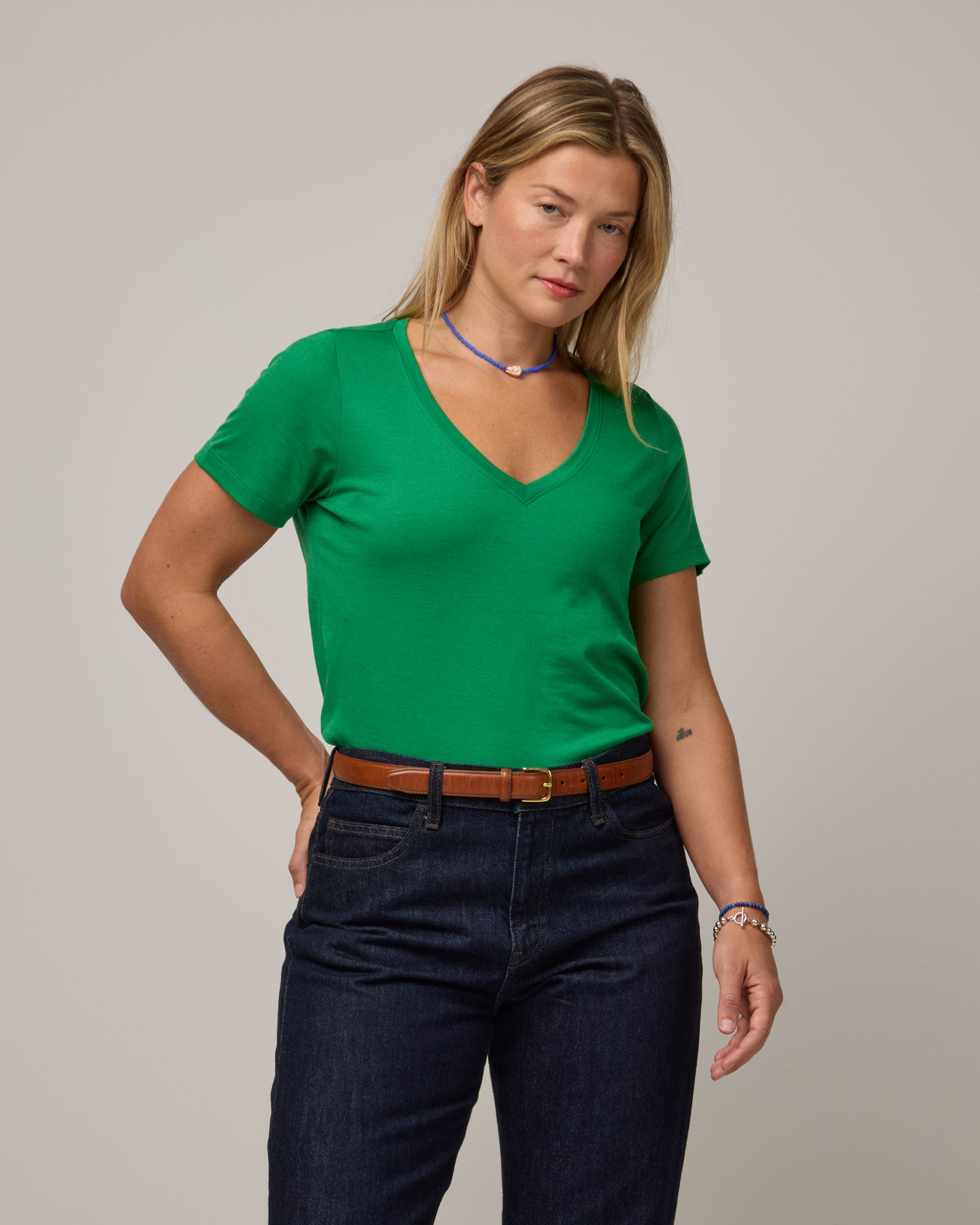 Model wearing Morgan V-Neck Tee in Verde, a bright Kelly green color. Morgan V-Neck Tee is a merino wool short sleeve, v-neck, regular fit tee available in sizes XS-3X.