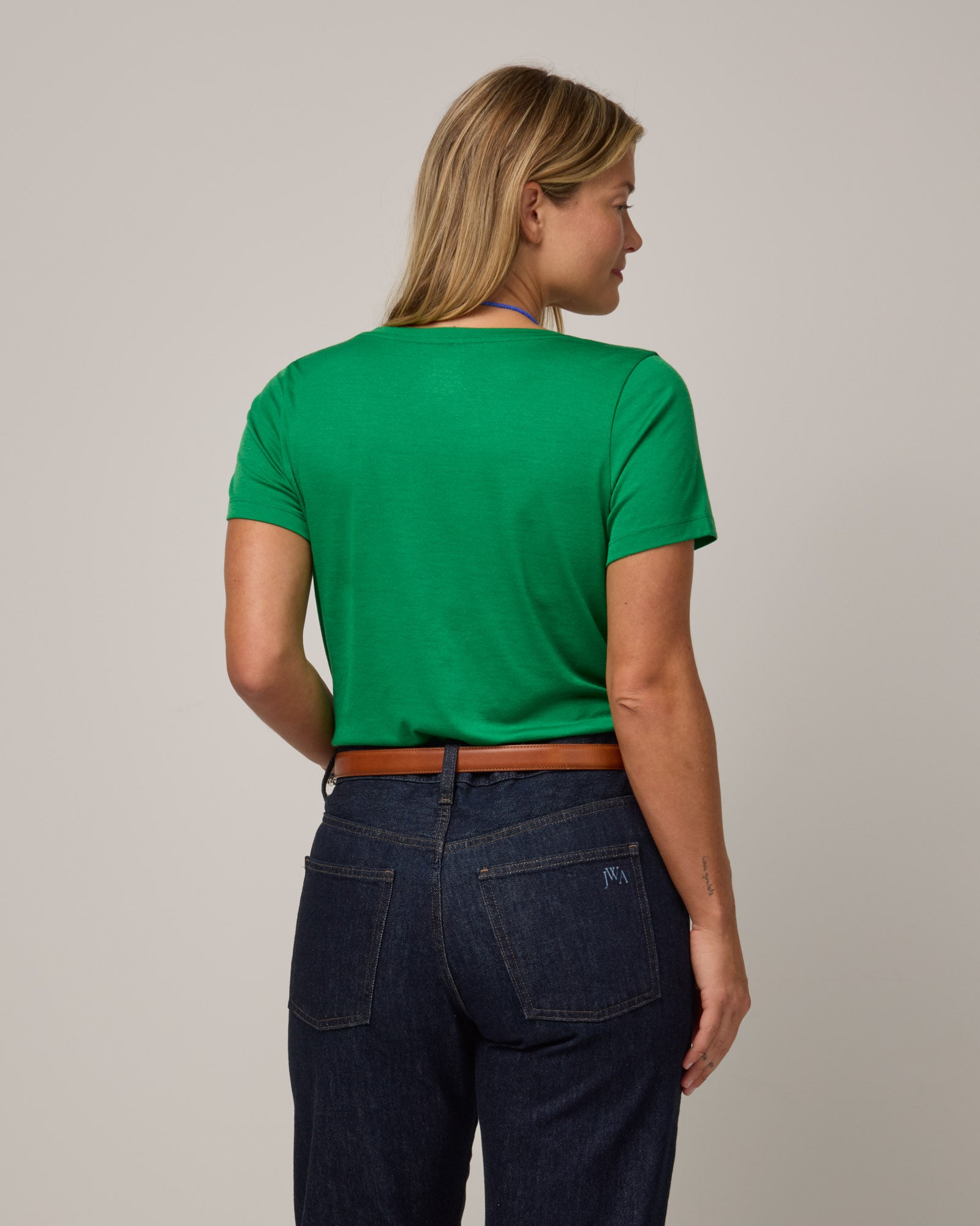 Model wearing Morgan V-Neck Tee in Verde, a bright Kelly green color. Morgan V-Neck Tee is a merino wool short sleeve, v-neck, regular fit tee available in sizes XS-3X.