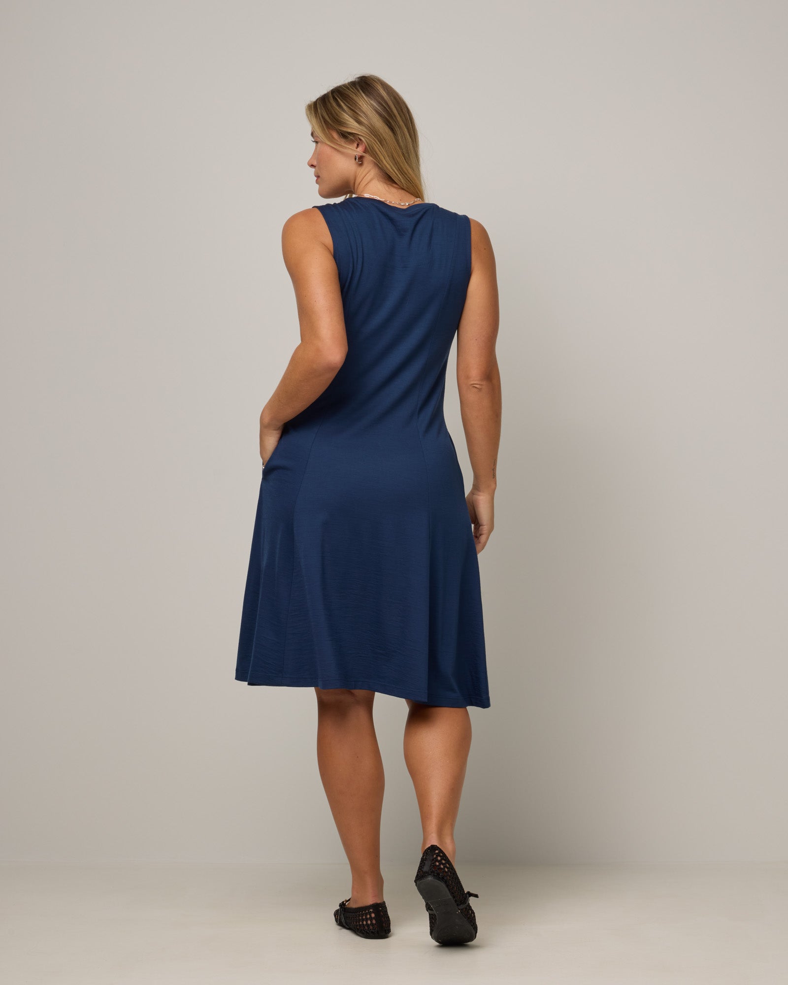 Model wearing Flora Swing Dress in Marine Blue, a deep royal blue color. Flora Swing Dress is a merino wool sleeveless, scoop neck, knee length swing dress with pockets available in sizes XS-3X.