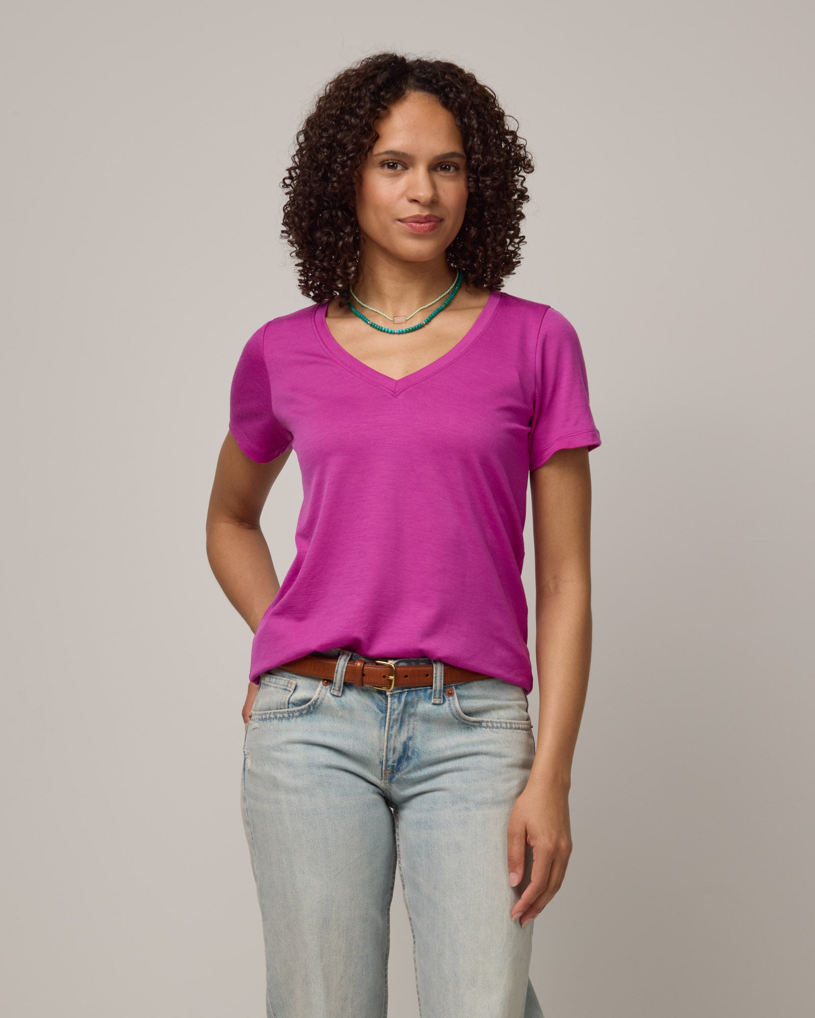 Model wearing Morgan V-Neck Tee in Petunia, a bright berry pink color. Morgan V-Neck Tee is a merino wool short sleeve, v-neck, regular fit tee available in sizes XS-3X.