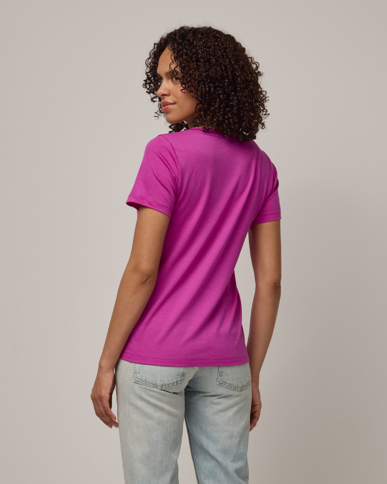 Model wearing Morgan V-Neck Tee in Petunia, a bright berry pink color. Morgan V-Neck Tee is a merino wool short sleeve, v-neck, regular fit tee available in sizes XS-3X.