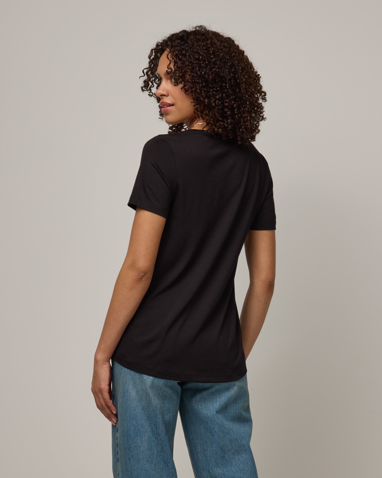 Model wearing Stella Signature Scoop Neck Tee in Black. Stella Signature Scoop Neck Tee is a merino wool short sleeve, scoop neck, relaxed fit tee available in sizes XS-3X.