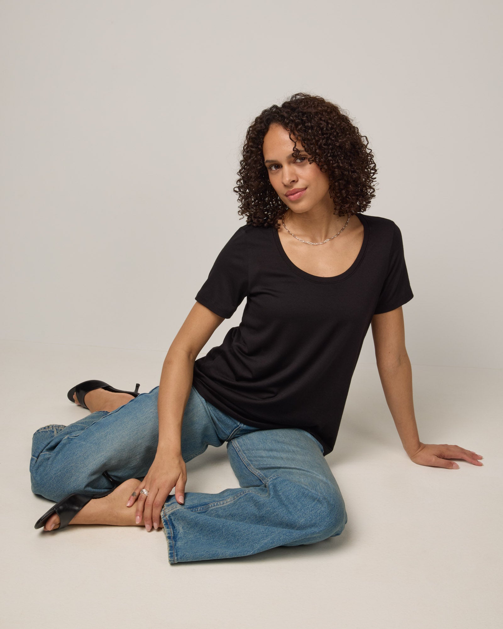 Model wearing Stella Signature Scoop Neck Tee in Black. Stella Signature Scoop Neck Tee is a merino wool short sleeve, scoop neck, relaxed fit tee available in sizes XS-3X.