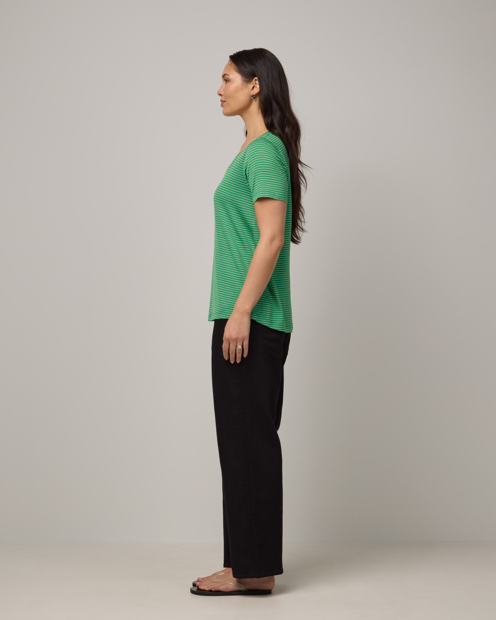 Model wearing Stella Scoop Neck Tee in Verde & Natural White Stripe. Stella Scoop Neck Tee is a merino wool short sleeve, scoop neck t-shirt available in sizes XS-3X.