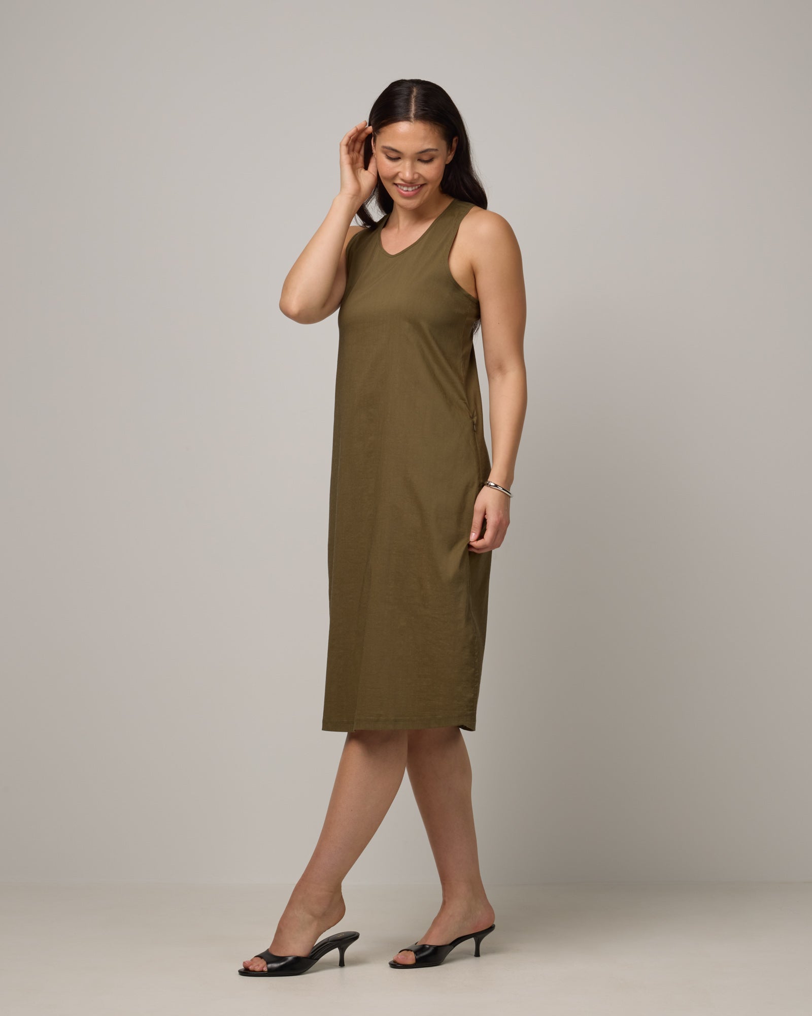 Model wearing Acadia Racerback Dress in Olive. Acadia Racerback Dress is a merino wool sleeveless, v-neck, midi length fitted dress available in sizes XS-XXL.