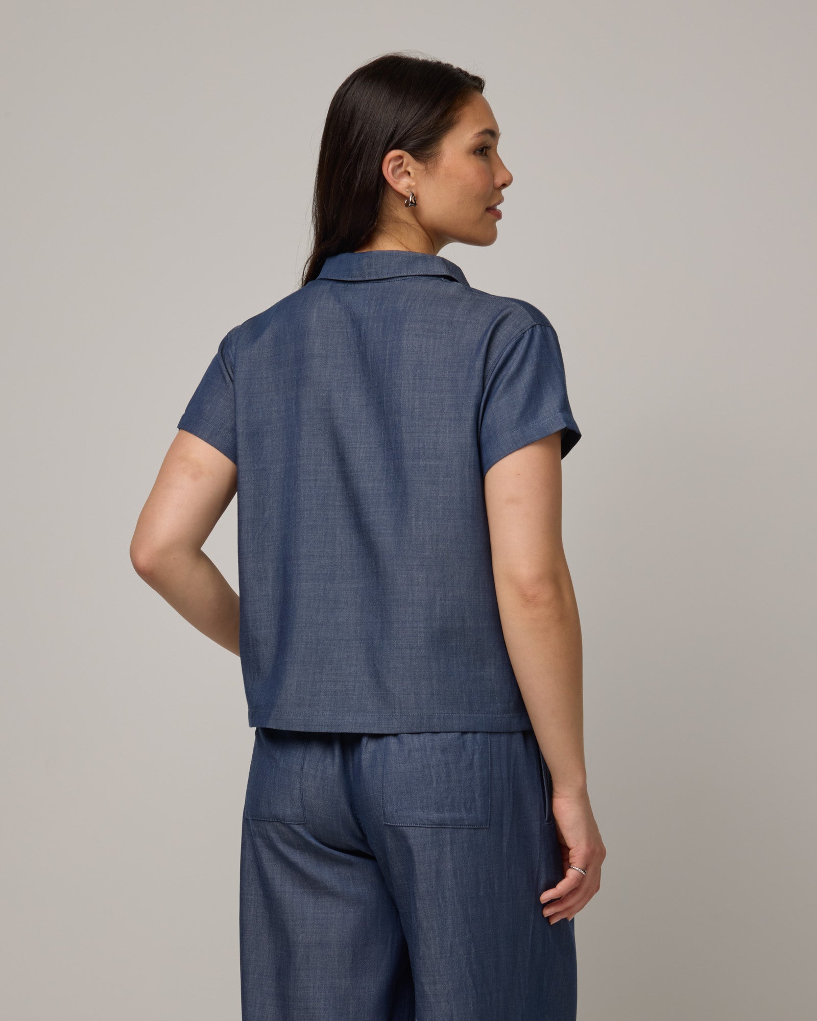 Model wearing Hollis Chambray Top in Dark Blue. Hollis Chambray Top is a merino wool short sleeve, collared top available in sizes XS-XXL. 
