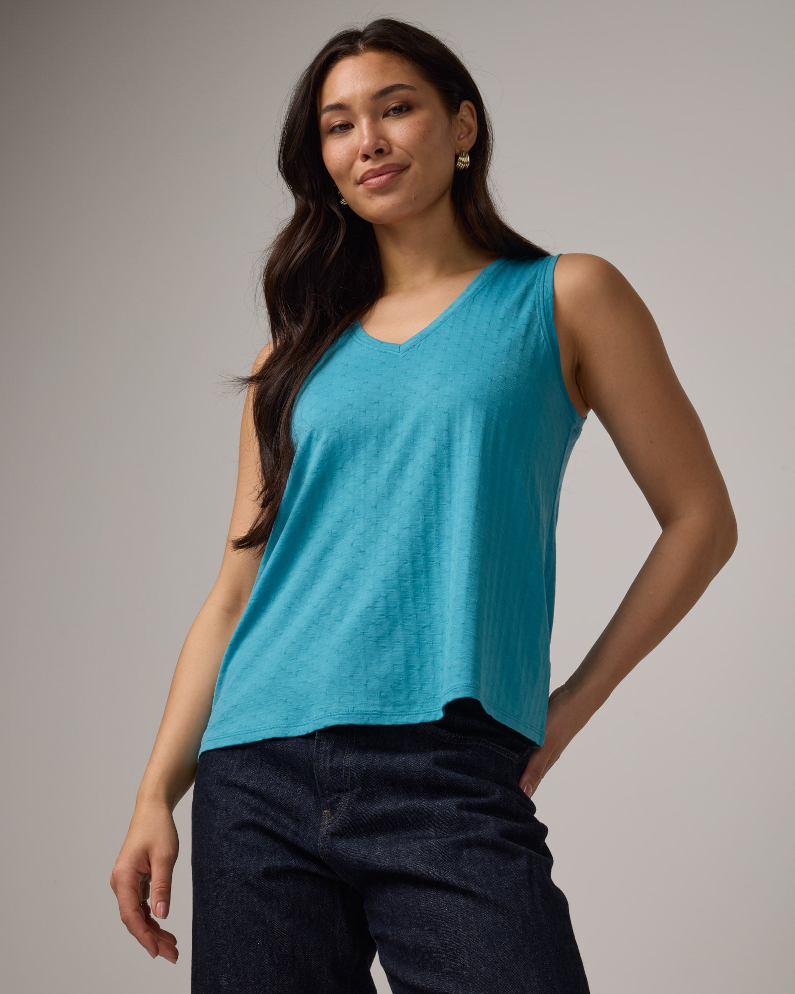 Model wearing Poppy Jacquard Reversible Tank in Sea Blue, a bright sky blue color. Poppy Signature Reversible Tank is a merino wool sleeveless, reversible, relaxed fit top available in sizes XS-3X.