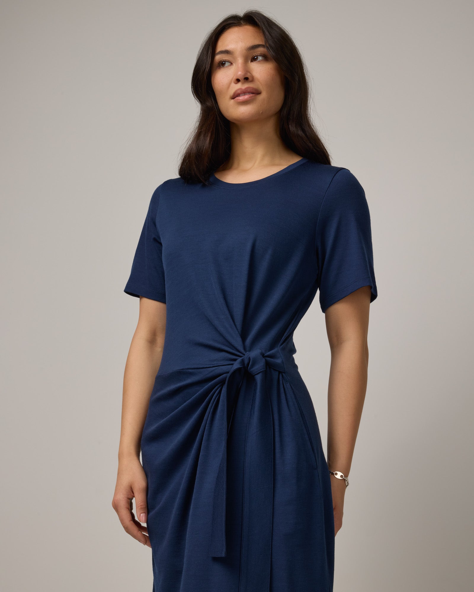 Model wearing Kelly Faux Tie Dress in Marine Blue, a deep royal blue color. Kelly Faux Tie Dress is a merino wool crew neck, short sleeve, knee length shift dress with pockets available in sizes XS-3X. 
