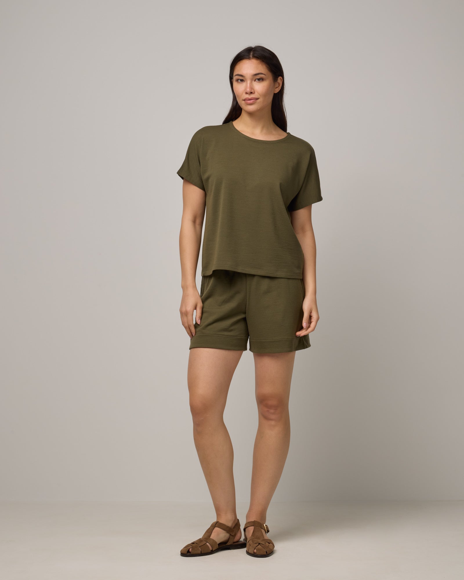 Model wearing Carina Sweatshirt Tee in Olive. Carina Sweatshirt Tee is a merino wool short sleeve, crew neck, relaxed fit boxy tee available in sizes XS-XXL.