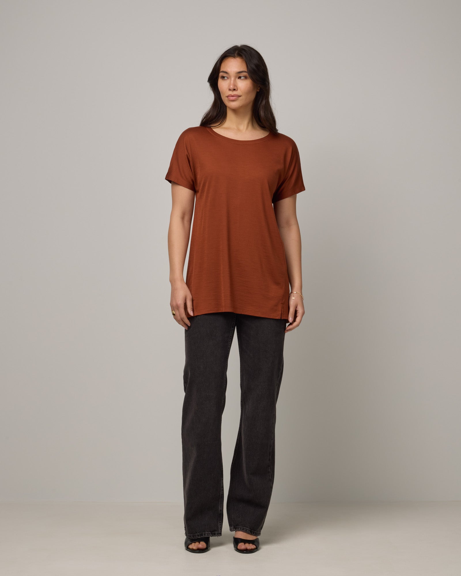 Model wearing Jade Tunic Tee in Cinnamon, a warm, rusty reddish-brown color. Jade Tunic Tee is a merino wool short sleeve, crew neck, relaxed fit tunic available in sizes XS-3X.