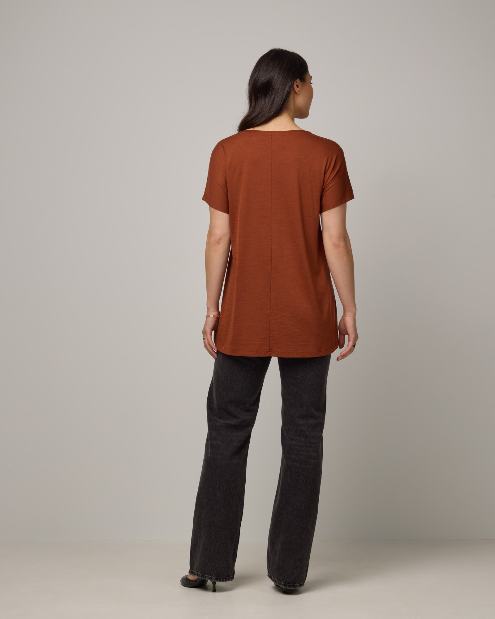 Model wearing Jade Tunic Tee in Cinnamon, a warm, rusty reddish-brown color. Jade Tunic Tee is a merino wool short sleeve, crew neck, relaxed fit tunic available in sizes XS-3X.