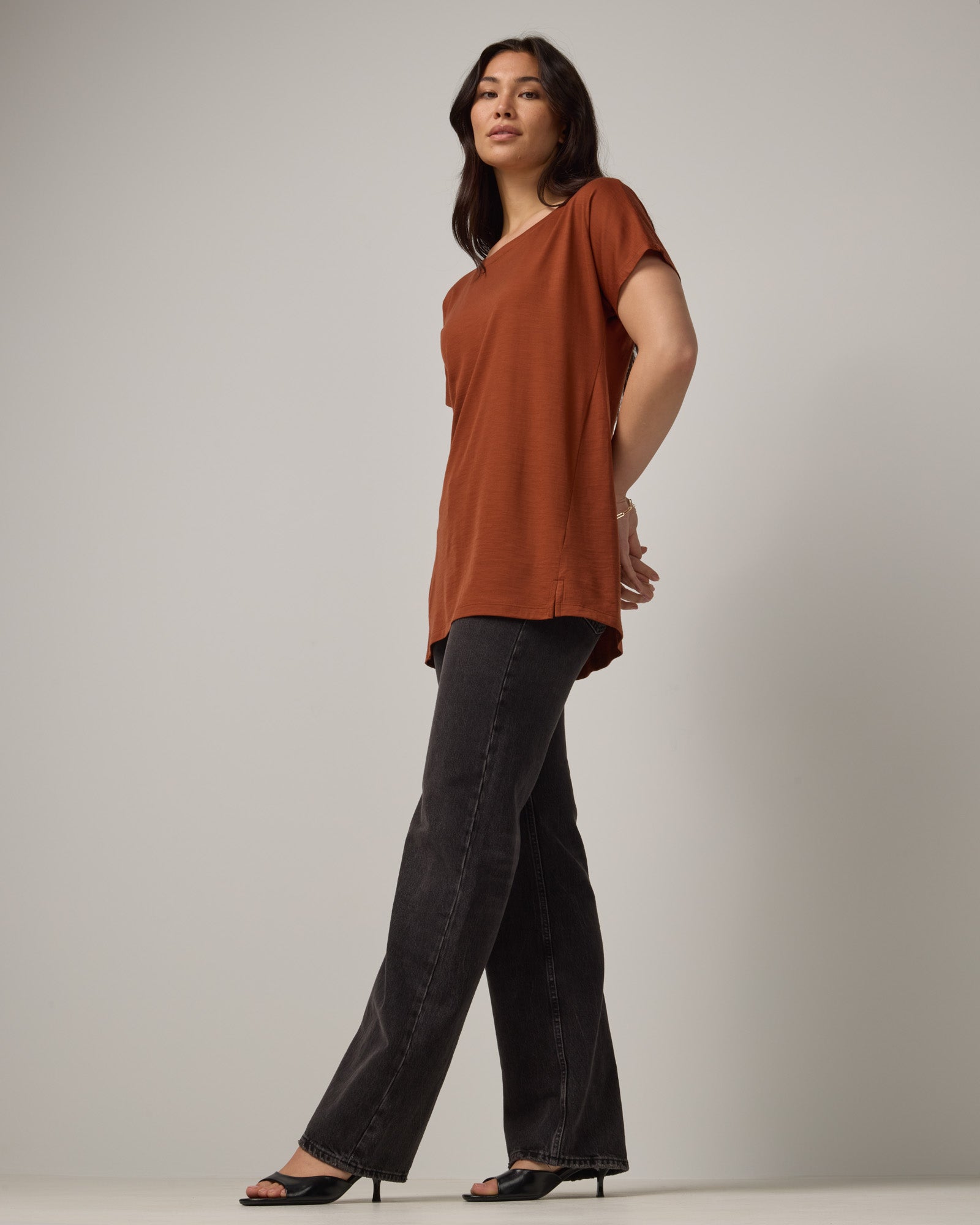 Model wearing Jade Tunic Tee in Cinnamon, a warm, rusty reddish-brown color. Jade Tunic Tee is a merino wool short sleeve, crew neck, relaxed fit tunic available in sizes XS-3X.