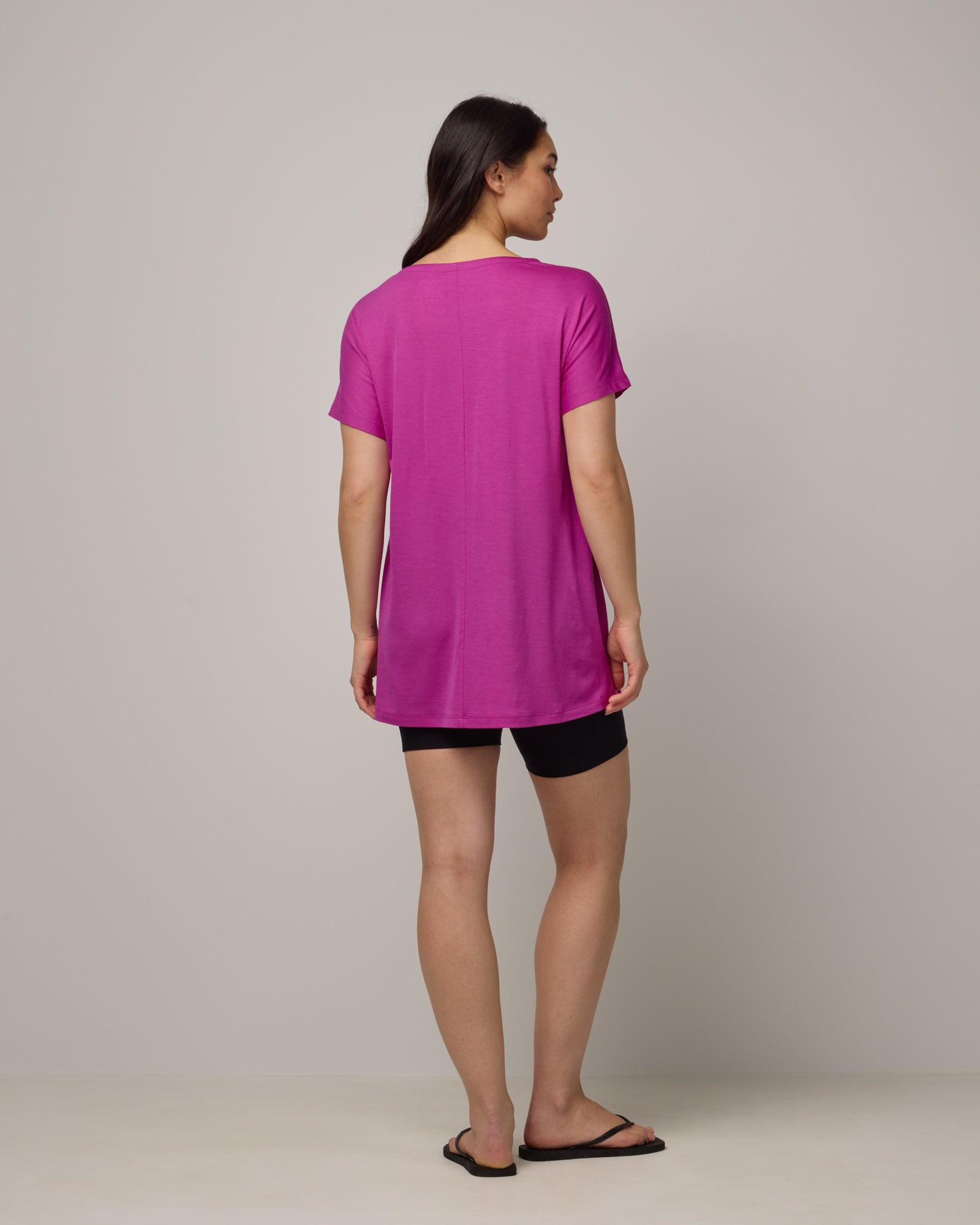 Model wearing Jade Tunic Tee in Petunia, a bright fuchsia pink color. Jade Tunic Tee is a merino wool short sleeve, crew neck, relaxed fit tunic available in sizes XS-3X.