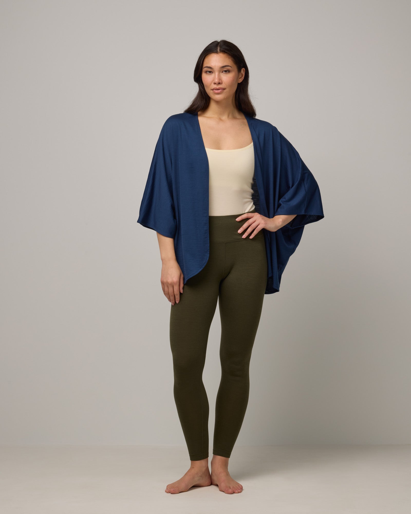 Model wearing Roam Legging in Forest Night, a dark forest green color. Roam Legging is a lightweight merino wool legging with pockets available in sizes XS-3X.