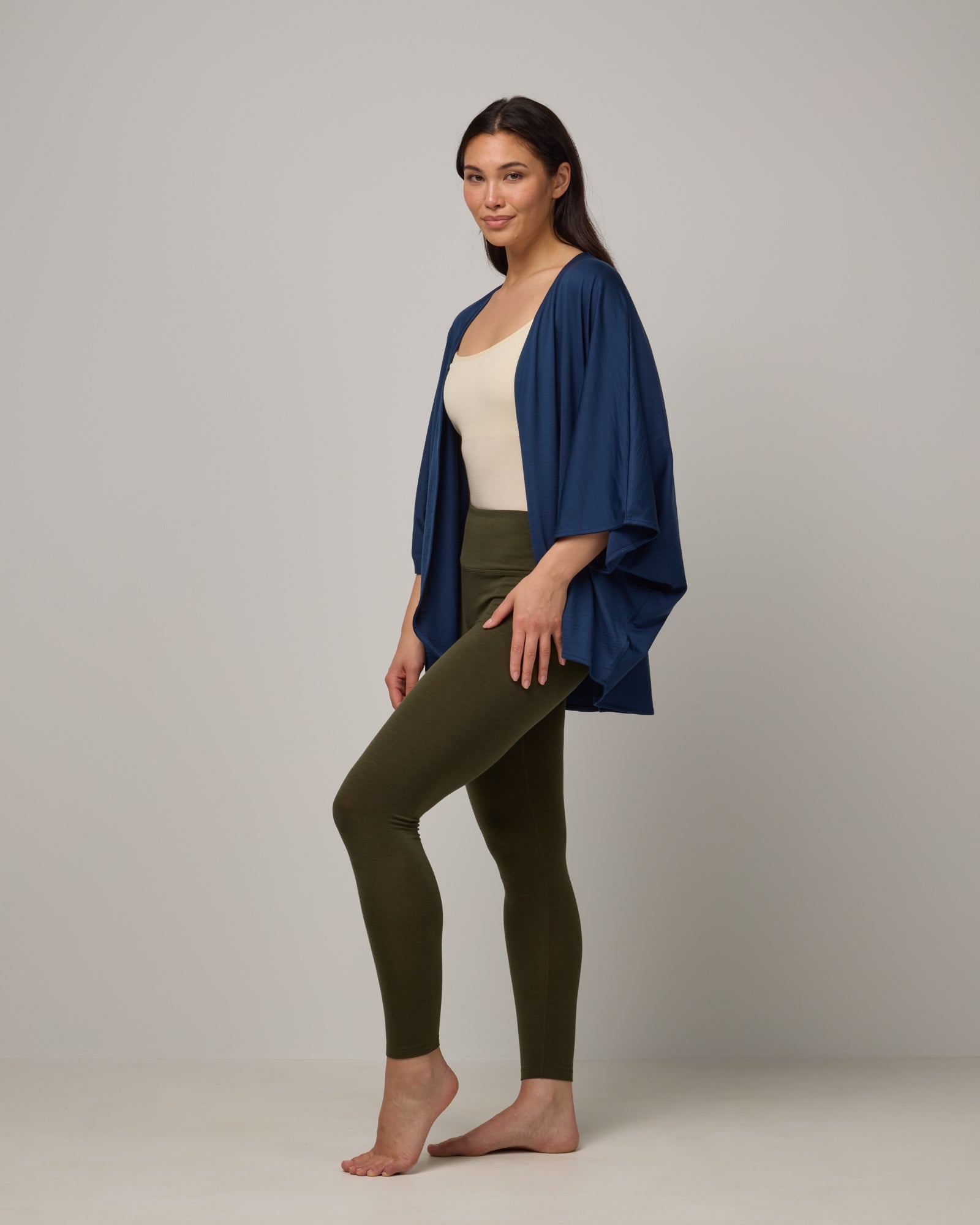 Model wearing Roam Legging in Forest Night, a dark forest green color. Roam Legging is a lightweight merino wool legging with pockets available in sizes XS-3X.