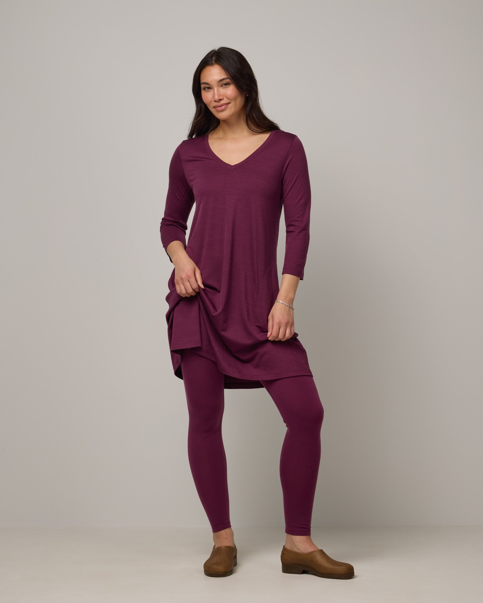 Model wearing Roam Legging in Plum, a reddish-purple color. Roam Legging is a lightweight merino wool legging with pockets available in sizes XS-3X.