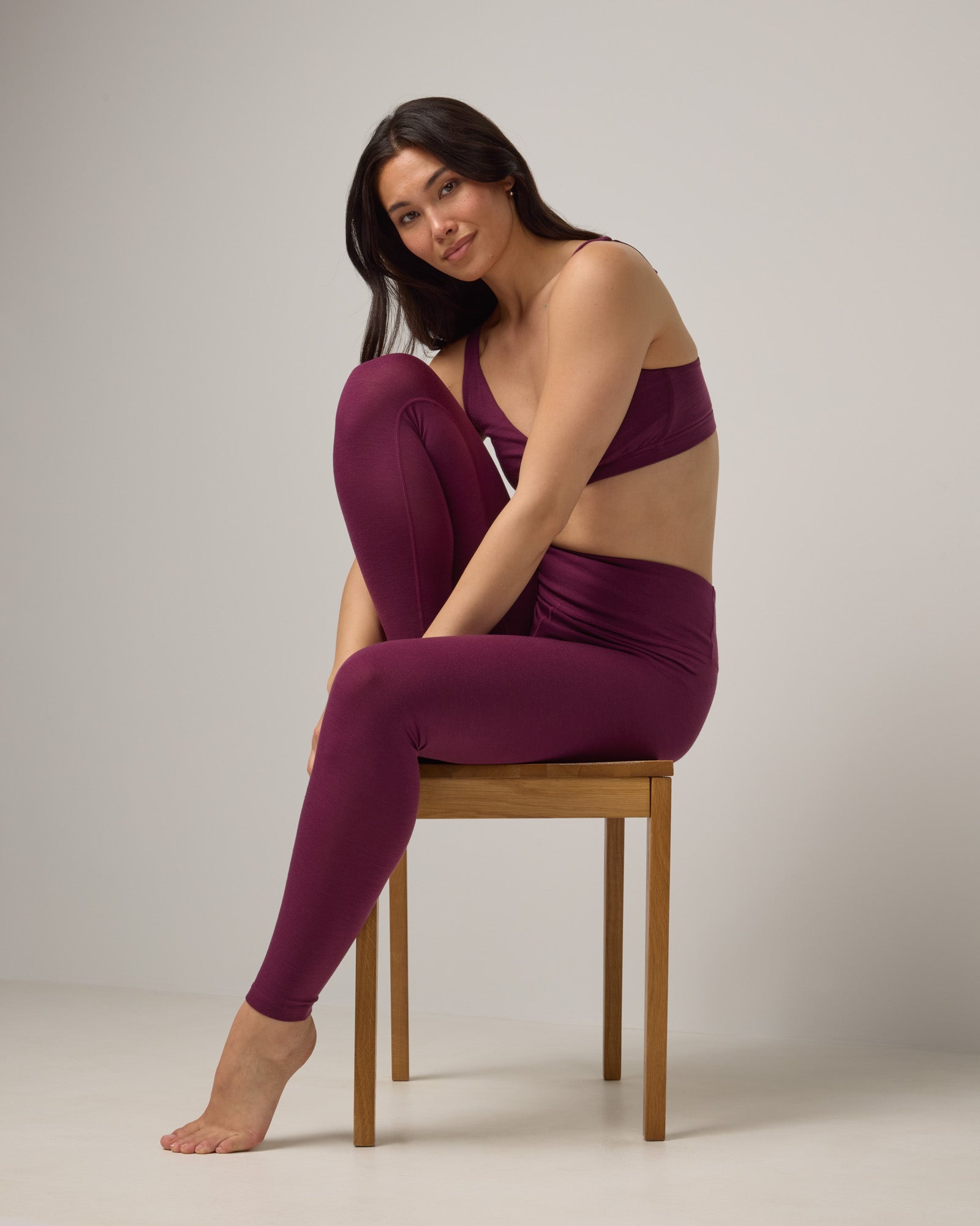 Model wearing Roam Legging in Plum, a reddish-purple color. Roam Legging is a lightweight merino wool legging with pockets available in sizes XS-3X.