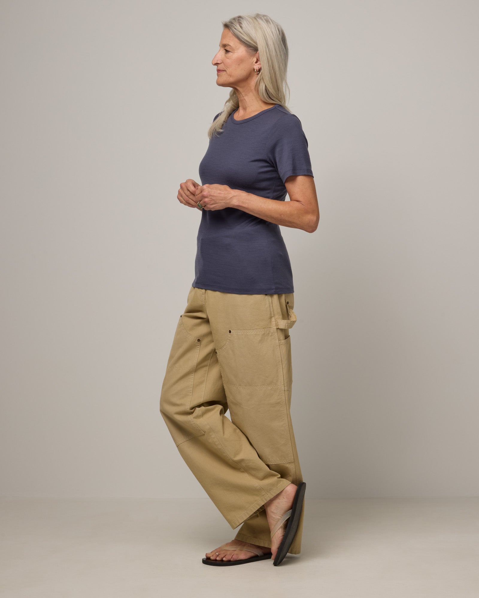 Model wearing Cara 100% Wool Fitted Tee in Odyssey Gray, a slate blue-gray color. Cara 100% Wool Fitted Tee is a merino wool short sleeve, crew neck, slim fit tee available in sizes XS-3X.