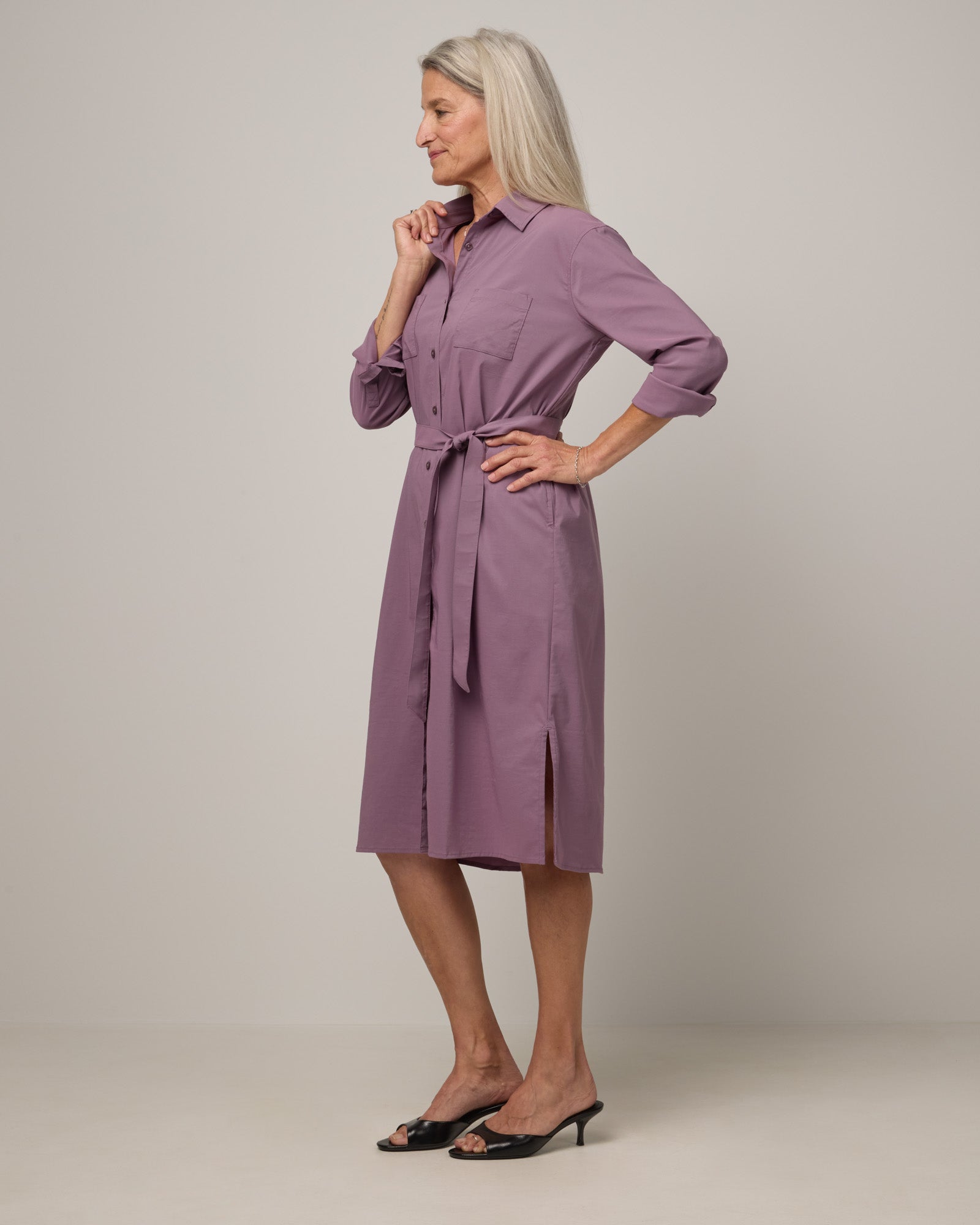 Model wearing Victoria Shirt Dress in Lavender. Victoria Shirt Dress is a merino wool long sleeve, midi length, button-front dress with pockets and removable belt available in sizes XS-XXL.