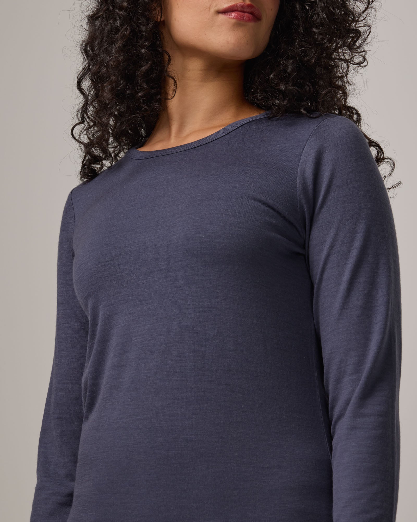 Model wearing Sloan 100% Fitted Tee in Odyssey Gray, a slate blue-gray color. Sloan 100% Fitted Tee is a merino wool long sleeve, crew neck, slim fit tee available in sizes XS-3X.