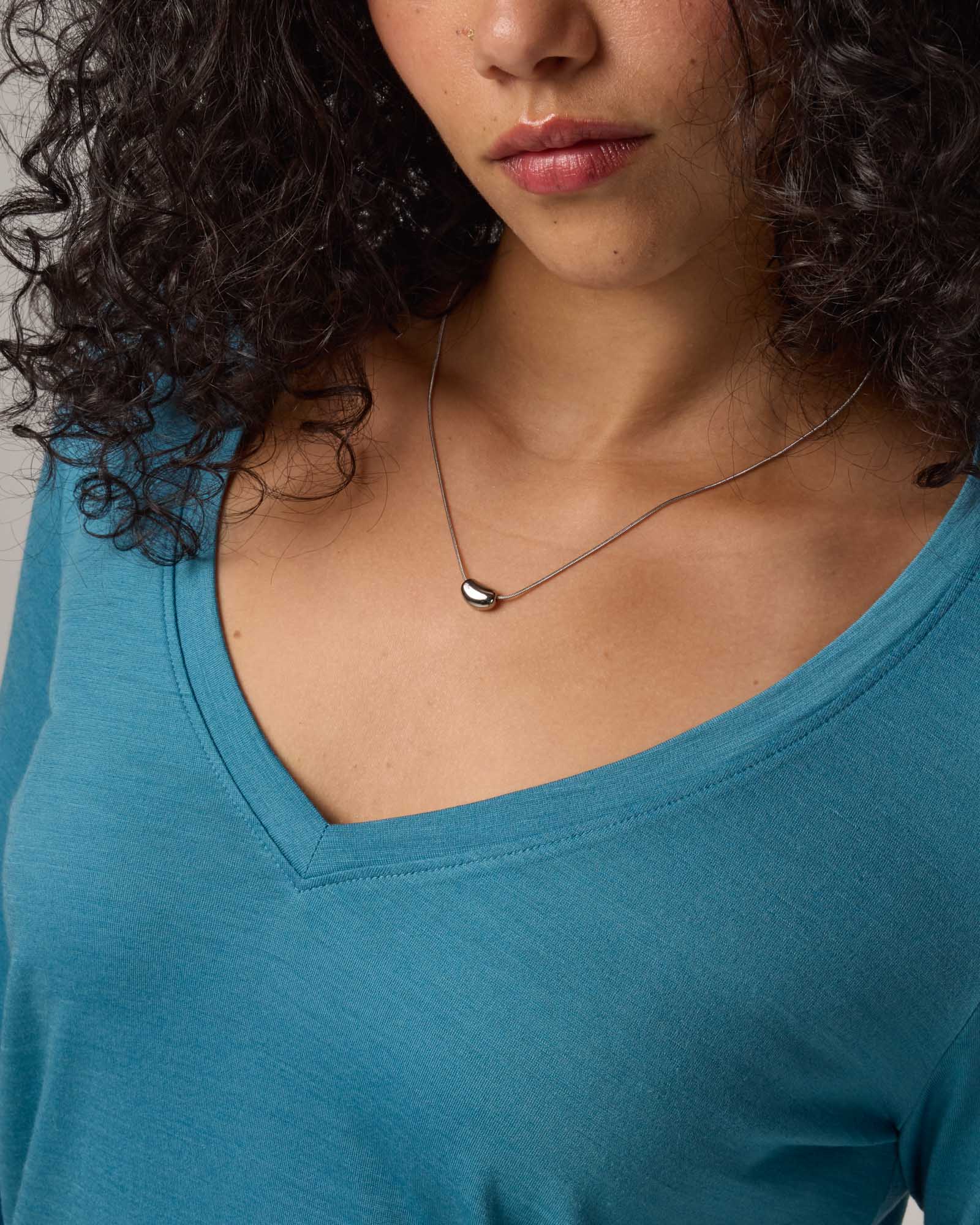 Model wearing Brenton V-Neck Tee in Alpine Blue, a glacier ice blue color. Brenton V-Neck Tee is a merino wool long sleeve, v-neck, regular fit tee available in sizes XS-3X.