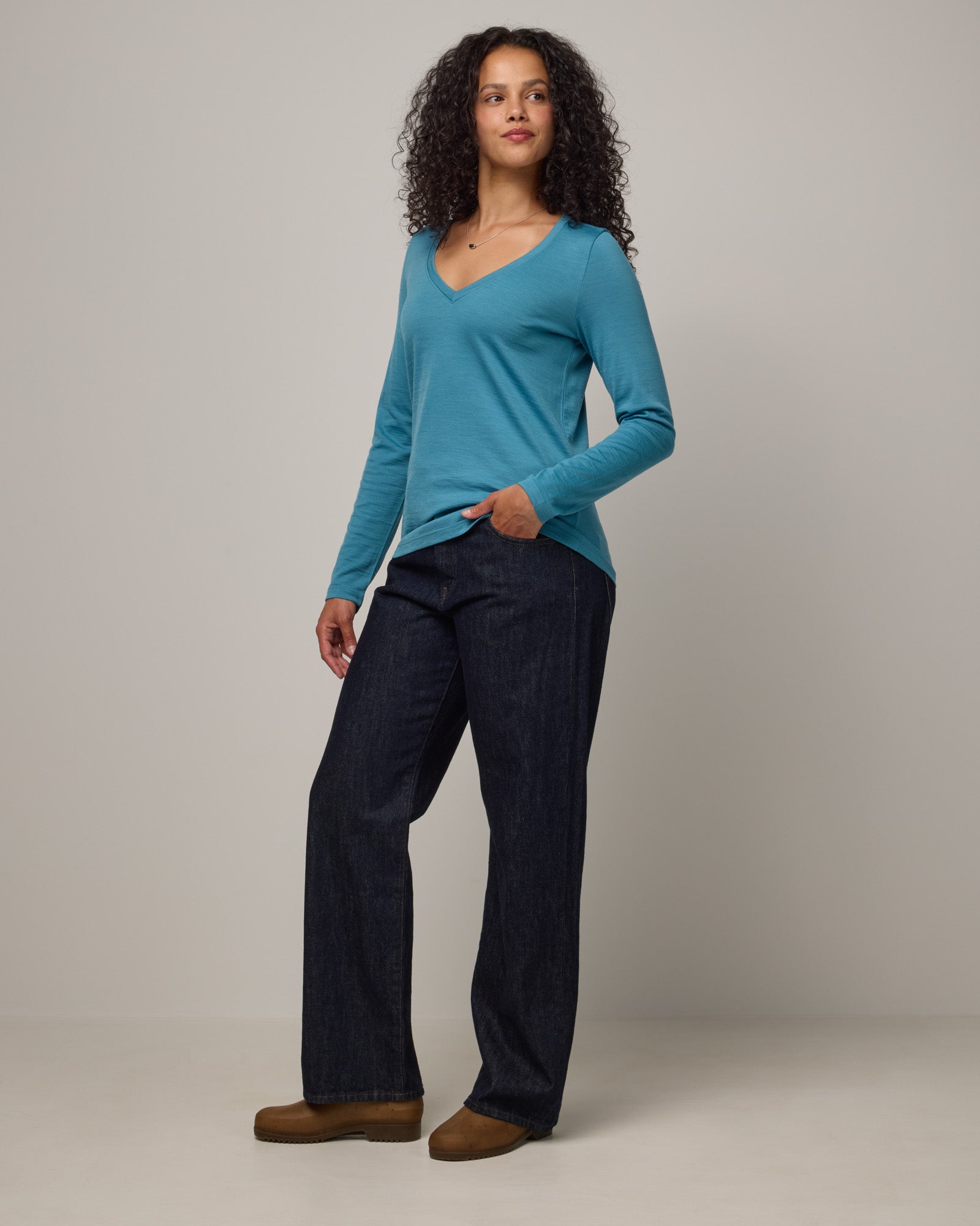 Model wearing Brenton V-Neck Tee in Alpine Blue, a glacier ice blue color. Brenton V-Neck Tee is a merino wool long sleeve, v-neck, regular fit tee available in sizes XS-3X.