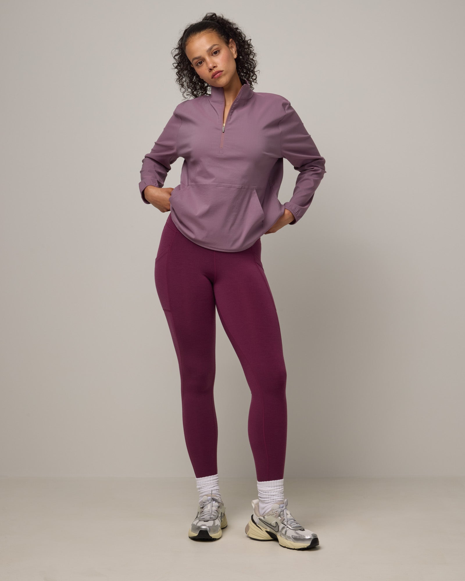 Model wearing Summit Pocket Legging in Plum, a reddish-purple color. Summit Pocket Legging is a merino wool legging with pockets available in sizes XS-3X Regular, S-XXL Long.