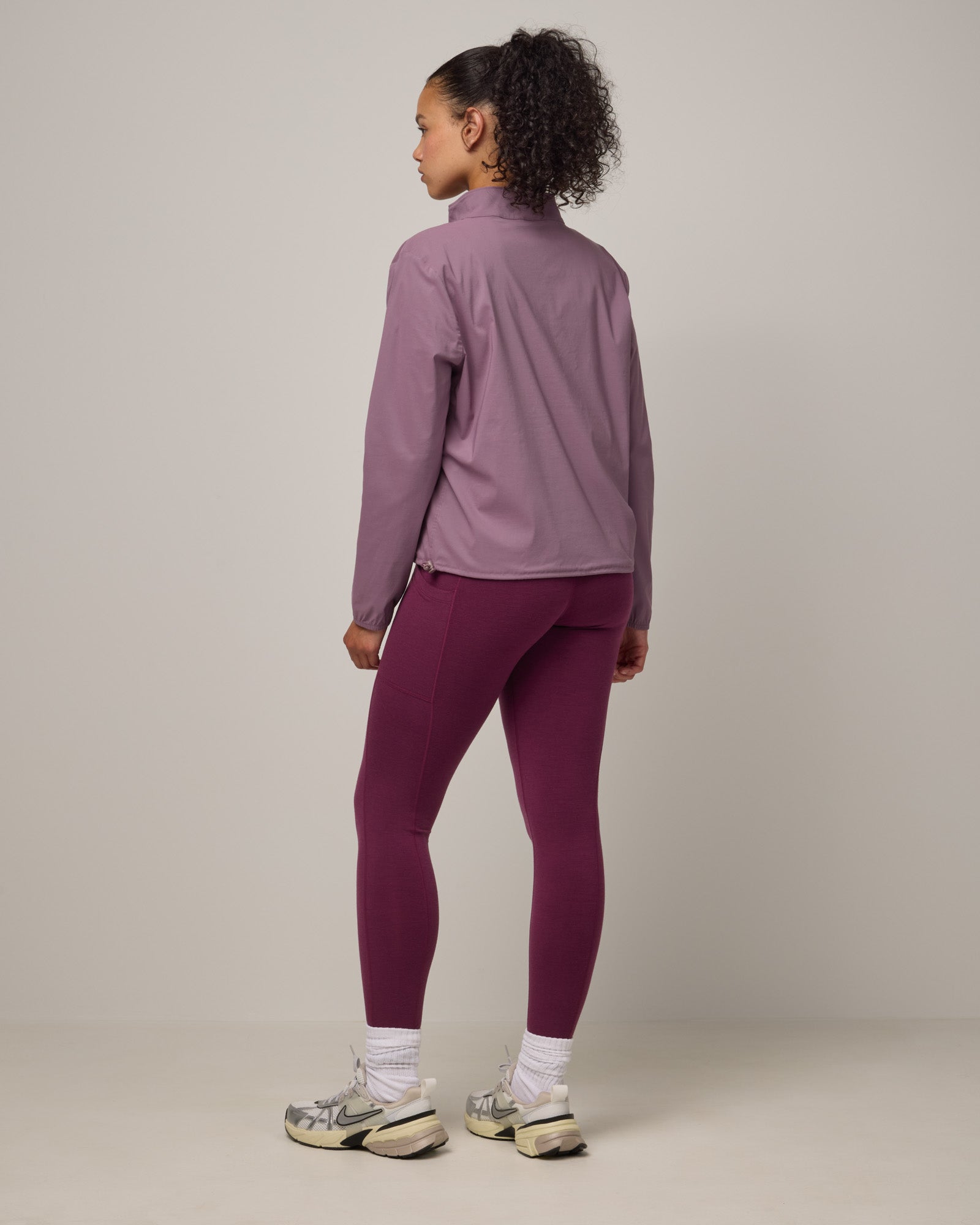 Model wearing Summit Pocket Legging in Plum, a reddish-purple color. Summit Pocket Legging is a merino wool legging with pockets available in sizes XS-3X Regular, S-XXL Long.