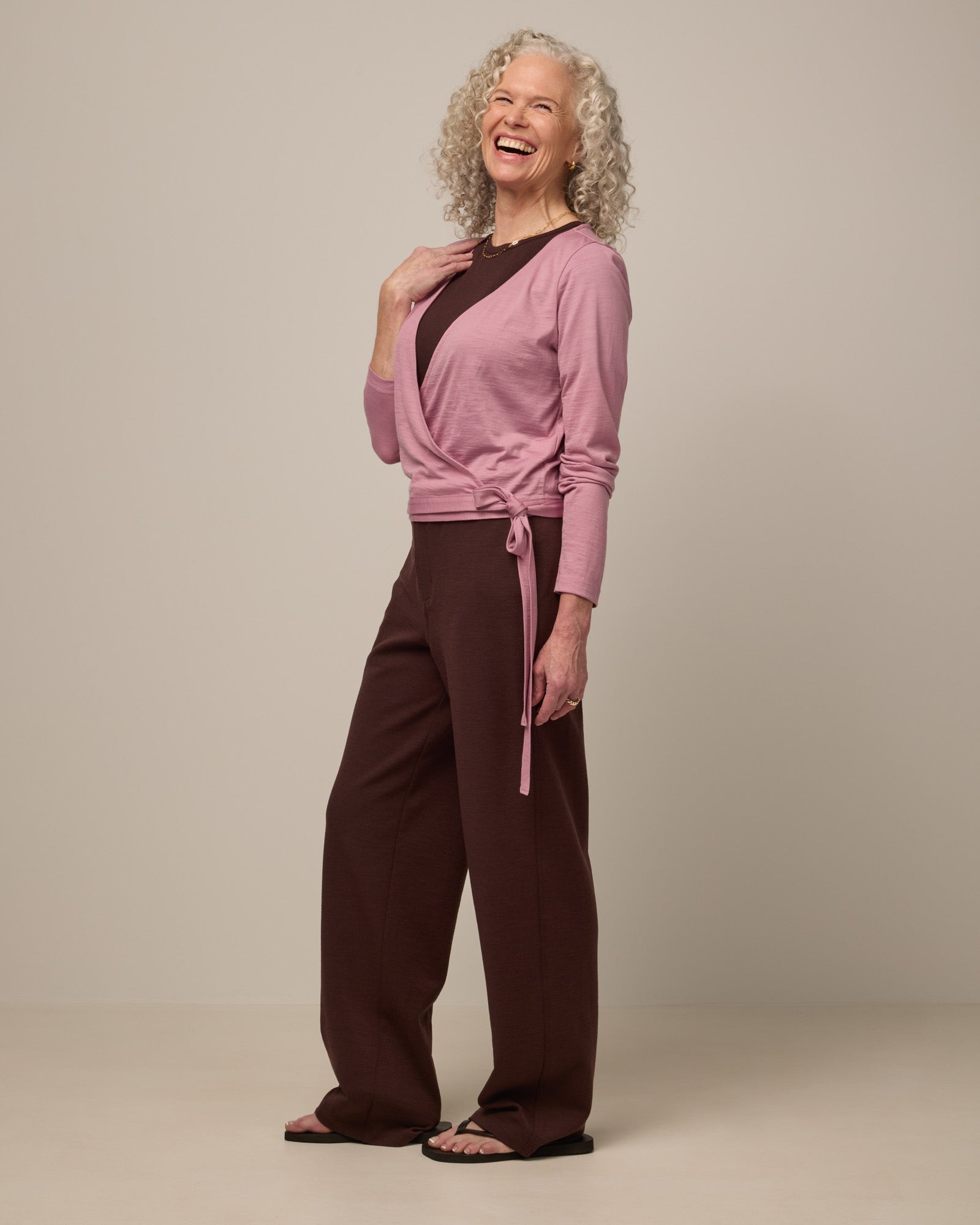 Model wearing Natalia Wrap Top in Ballet Pink, a muted light pink color. Natalia Wrap Top is a merino wool long sleeve, v-neck, slim fit top available in sizes XS-3X.