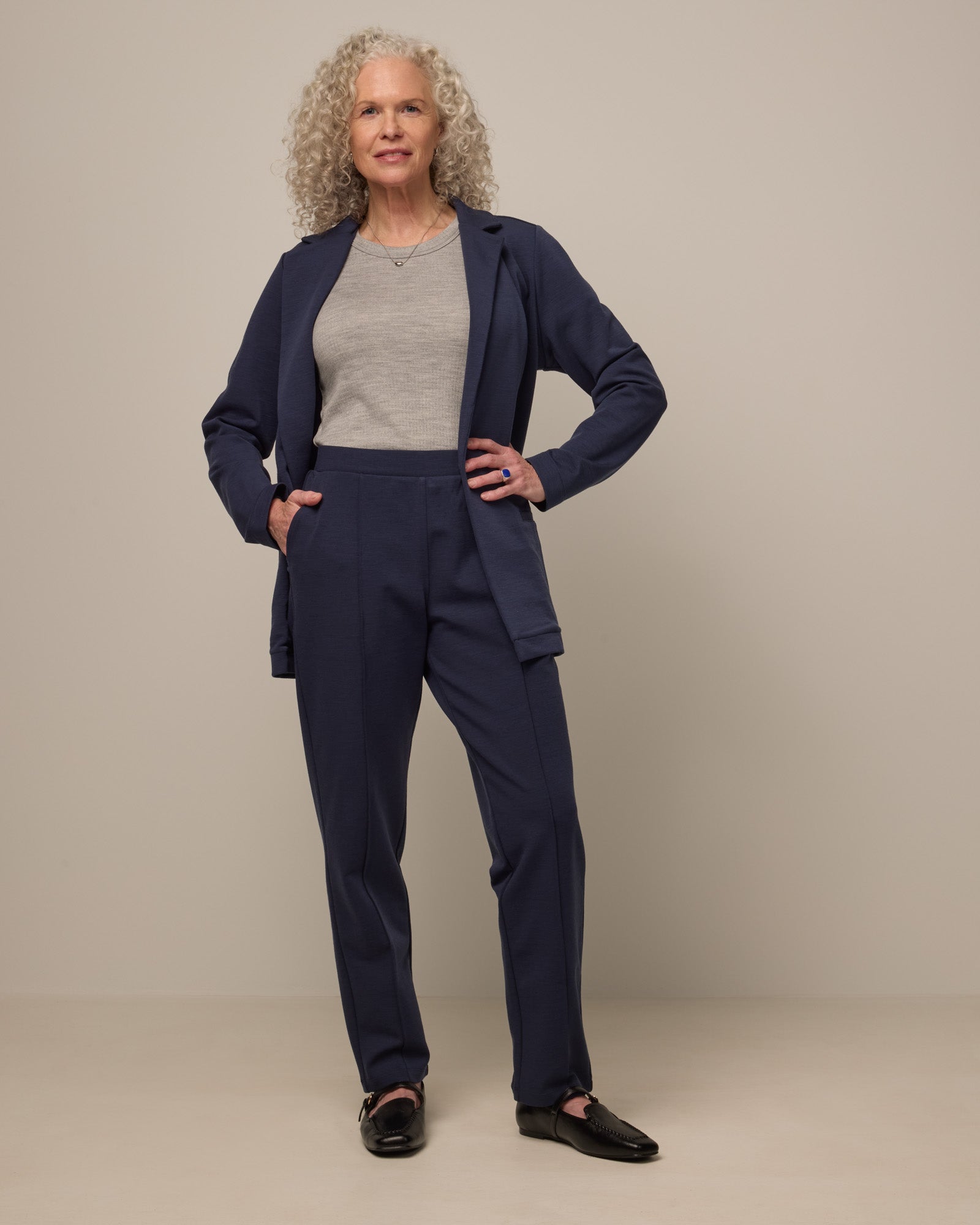 Model wearing Rosso Straight Ponte Pant in Washed Navy. Rosso Straight Ponte Pant is a merino wool pant with pockets available in sizes XS-3X Regular, S-XXL Long.