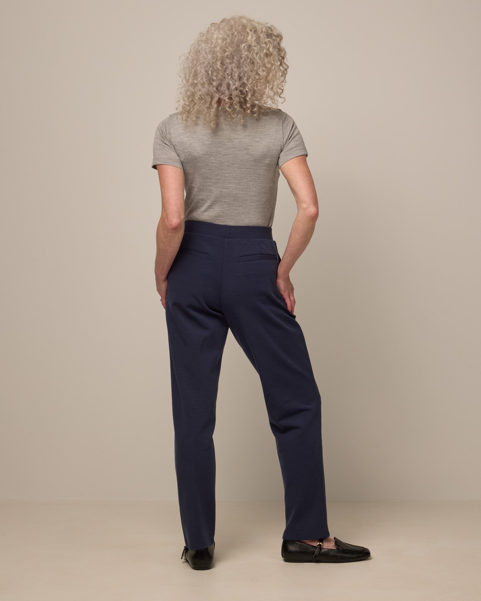 Model wearing Rosso Straight Ponte Pant in Washed Navy. Rosso Straight Ponte Pant is a merino wool pant with pockets available in sizes XS-3X Regular, S-XXL Long.