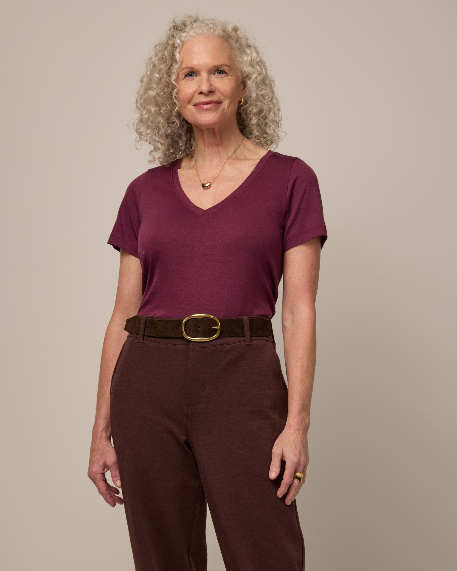 Model wearing Morgan V-Neck Tee in Plum, a reddish purple color. Morgan V-Neck Tee is a merino wool short sleeve, v-neck, regular fit tee available in sizes XS-3X.