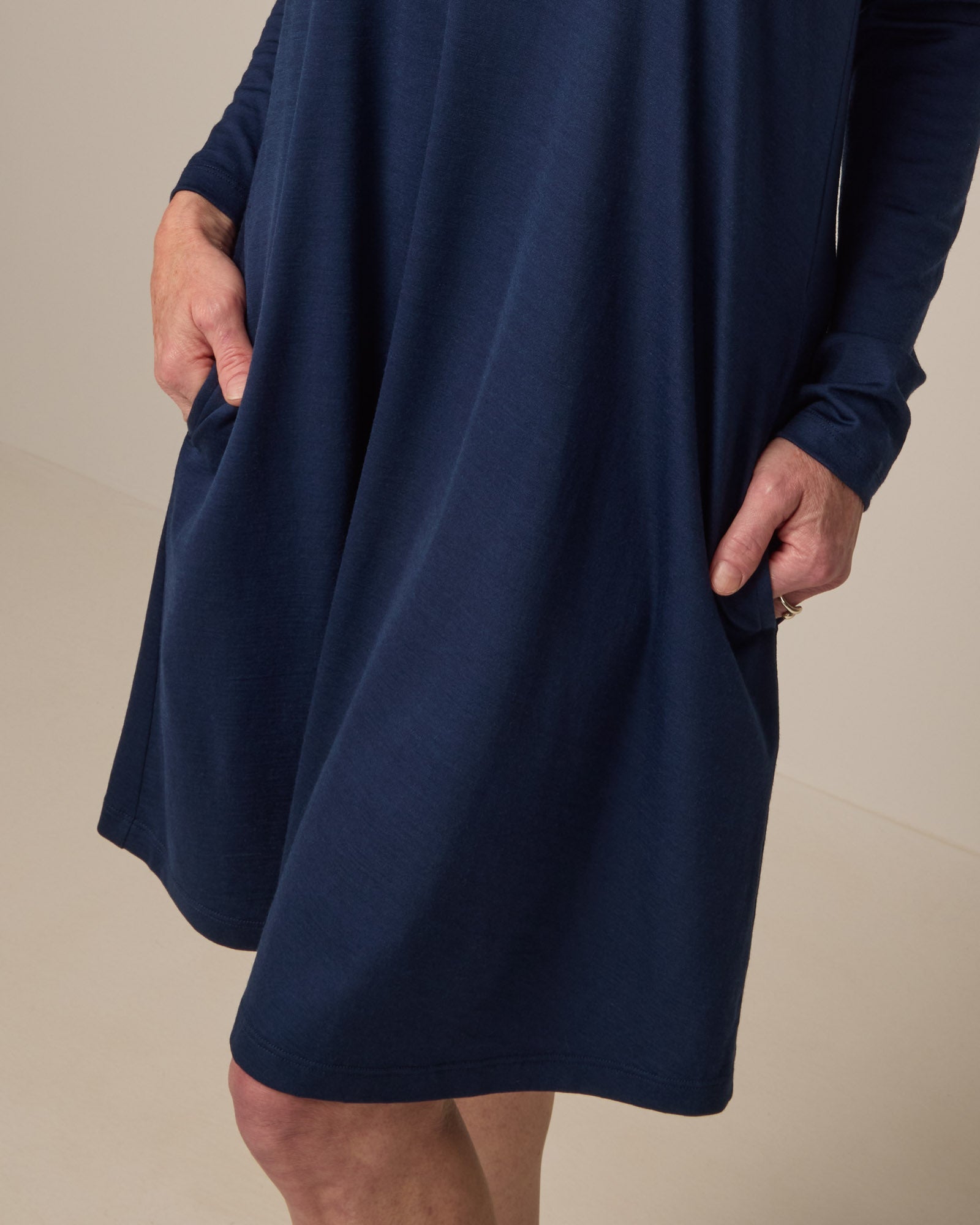 Model wearing Rowena Swing Dress in Marine Blue, a deep royal blue color. Rowena Swing Dress is a merino wool long sleeve, boatneck, knee length swing dress with pockets available in sizes XS-3X Regular, XS-3X Long.