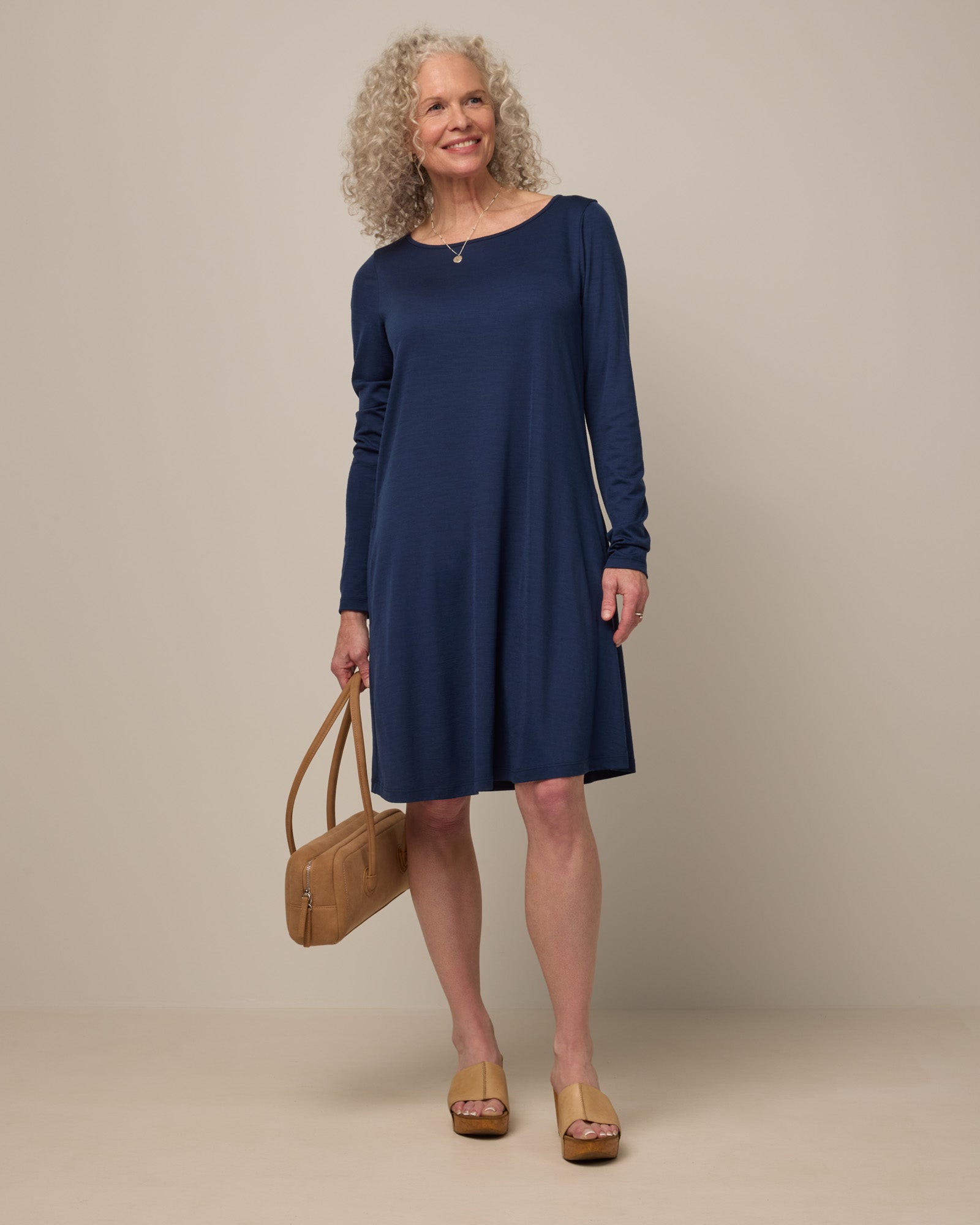 Model wearing Rowena Swing Dress in Marine Blue, a deep royal blue color. Rowena Swing Dress is a merino wool long sleeve, boatneck, knee length swing dress with pockets available in sizes XS-3X Regular, XS-3X Long.