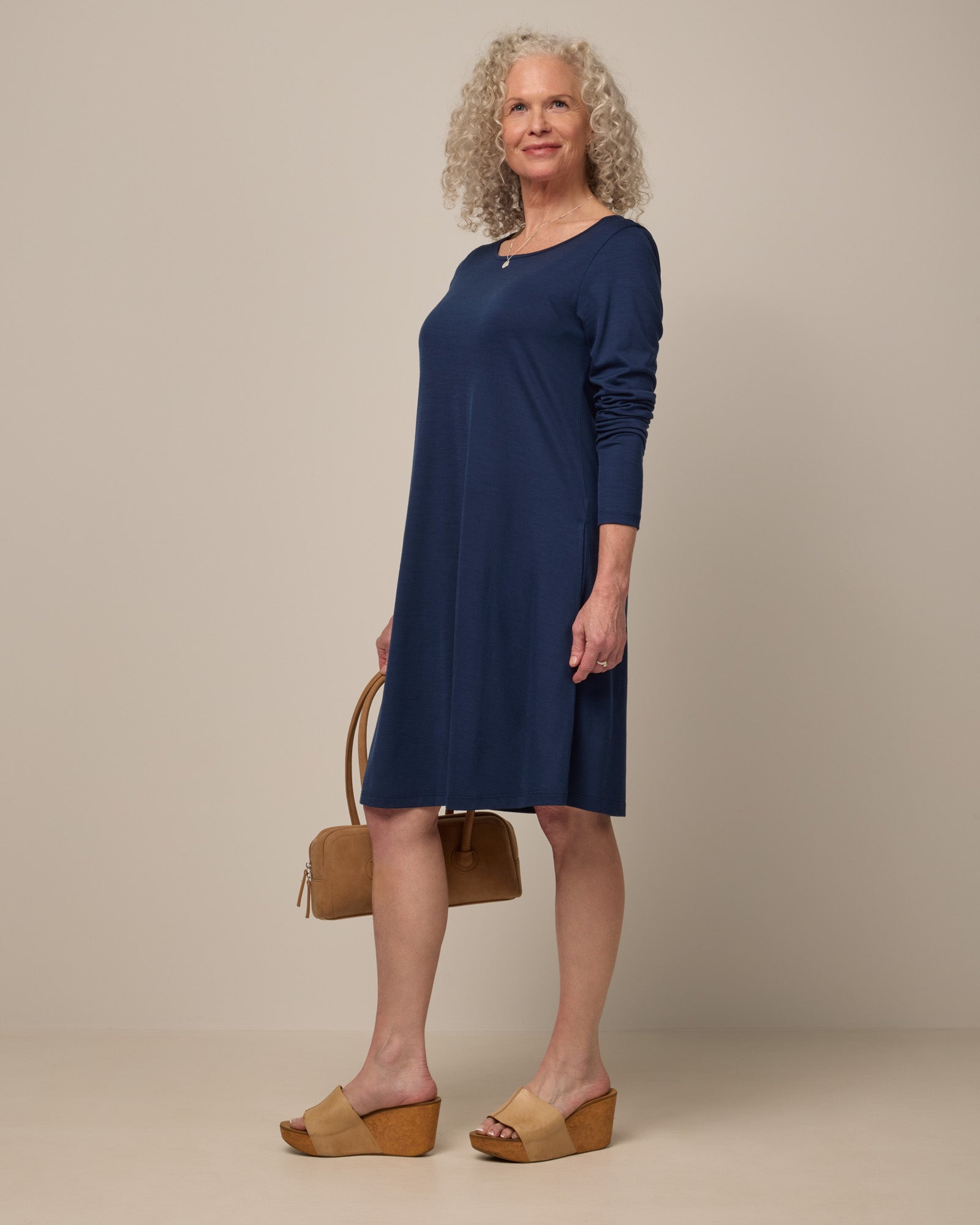 Model wearing Rowena Swing Dress in Marine Blue, a deep royal blue color. Rowena Swing Dress is a merino wool long sleeve, boatneck, knee length swing dress with pockets available in sizes XS-3X Regular, XS-3X Long.