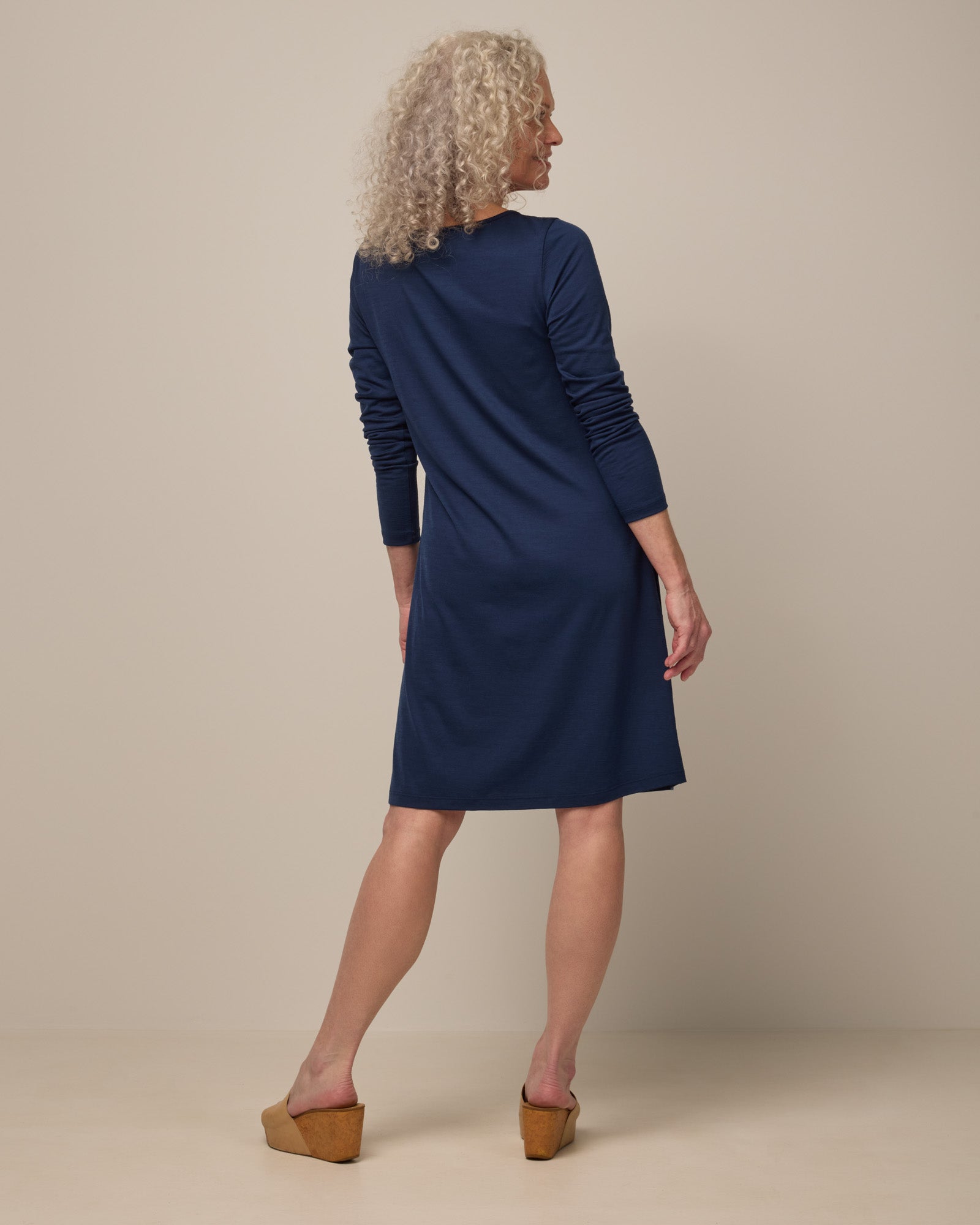 Model wearing Rowena Swing Dress in Marine Blue, a deep royal blue color. Rowena Swing Dress is a merino wool long sleeve, boatneck, knee length swing dress with pockets available in sizes XS-3X Regular, XS-3X Long.