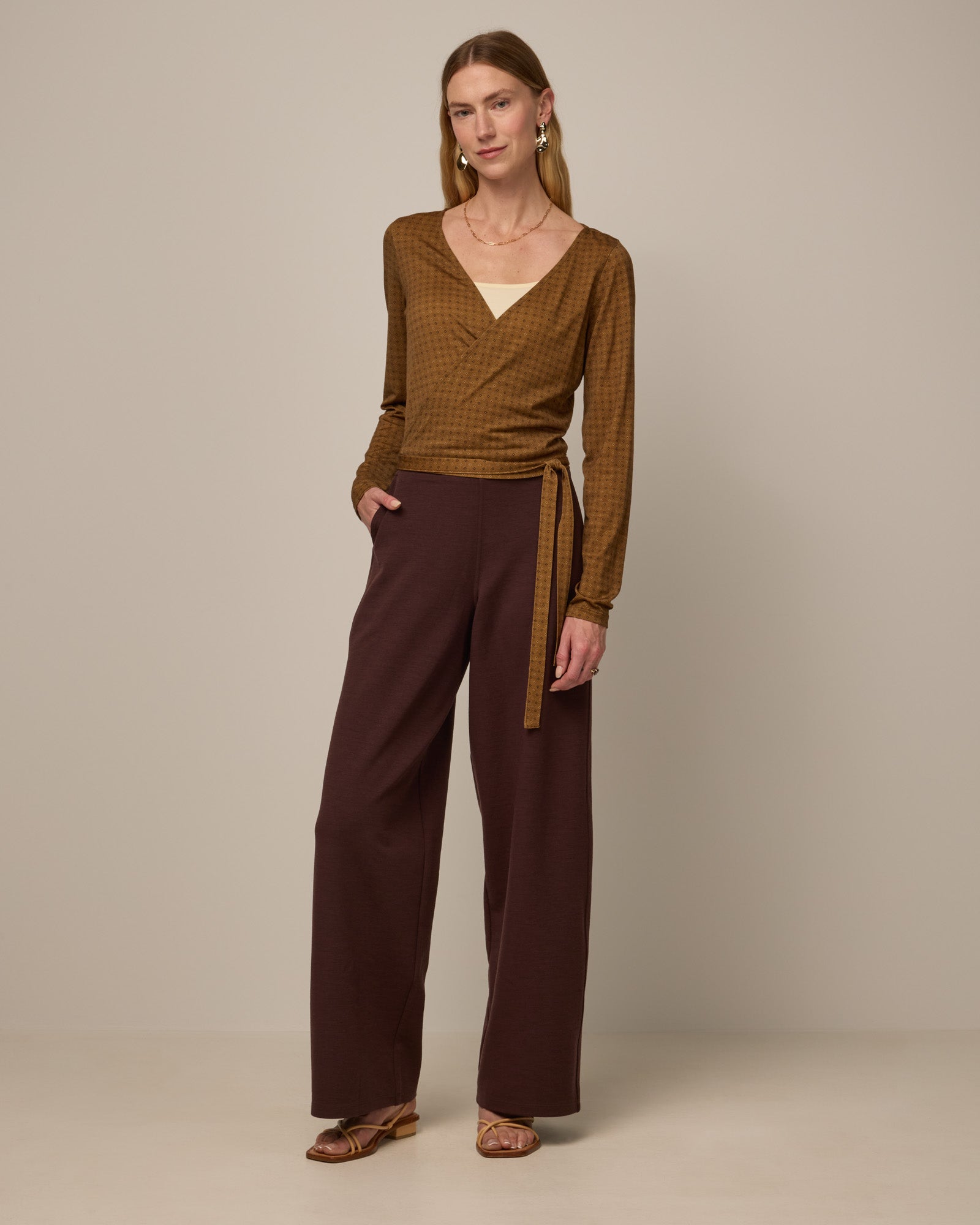 Model wearing Lane Wide Leg Ponte Pant in Espresso, a warm brown color. Lane Wide Leg Ponte Pant is a merino wool pant with pockets available in sizes XS-3X Regular, XS-XXL Long.